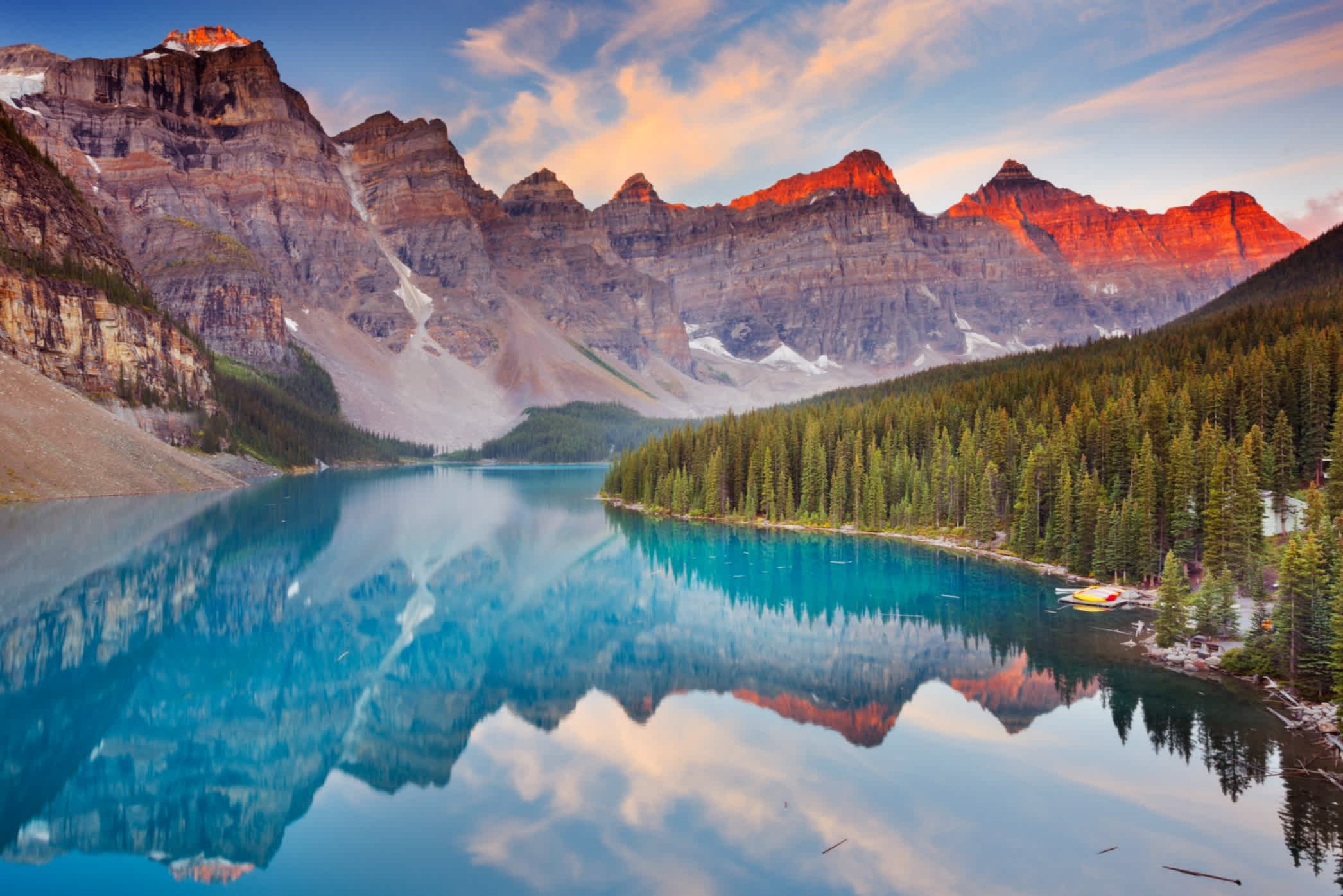 Blick auf die Rocky Mountains in Alberta mit kristallklarem See und Nadelwald.