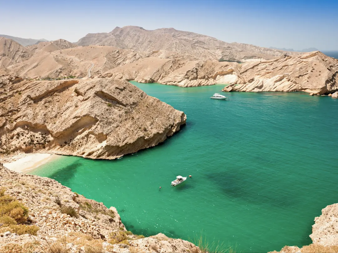 Die Lagune an der Küste Omans, von oben betrachtet, zeigt sich in faszinierenden Blau- und Türkistönen, umrahmt von schroffen Felsen