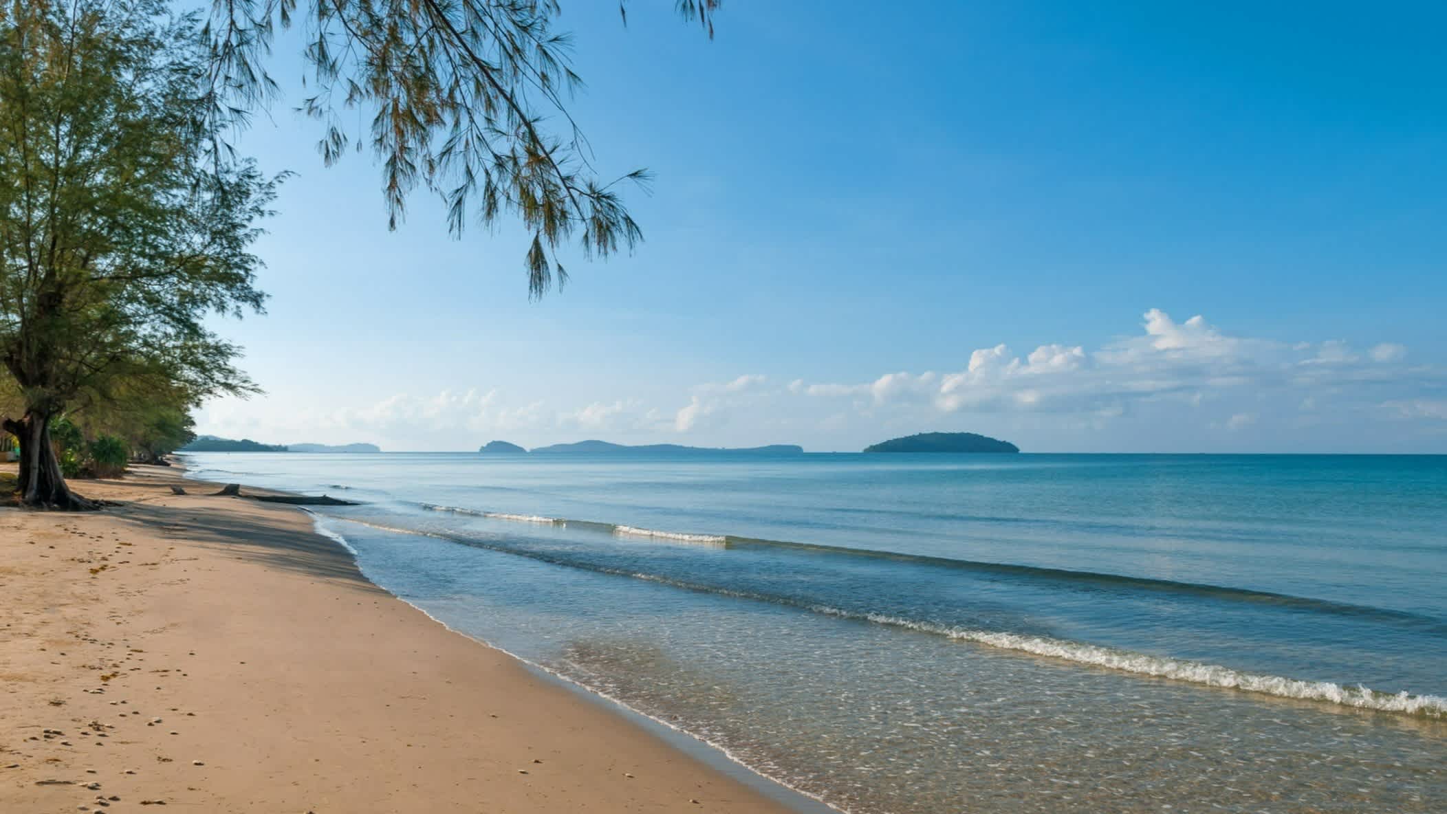 Sandstrand Otres Beach, Sihanoukville, Kambodscha bei blauem Himmel und mit Pinienbäumen am Strand.