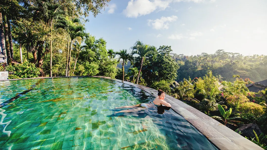 Frau in Infinity-Pool mit Blick auf tropische Natur, Ubud, Bali, Indonesien.