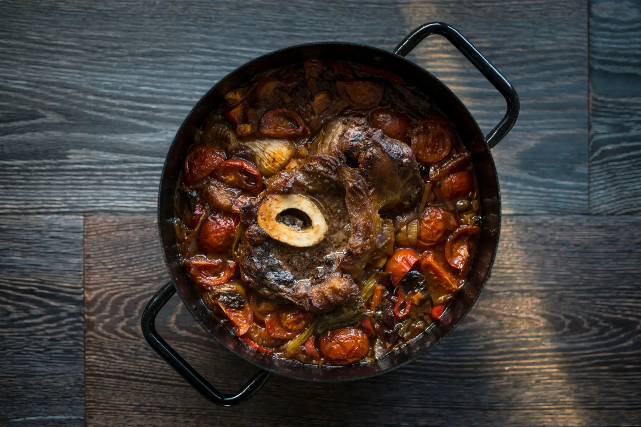 Italien, Essen, Ossobuco Gekochte Osso-Keufterschenkel mit Gemüse im gießeisernen Topf auf Holzrücken