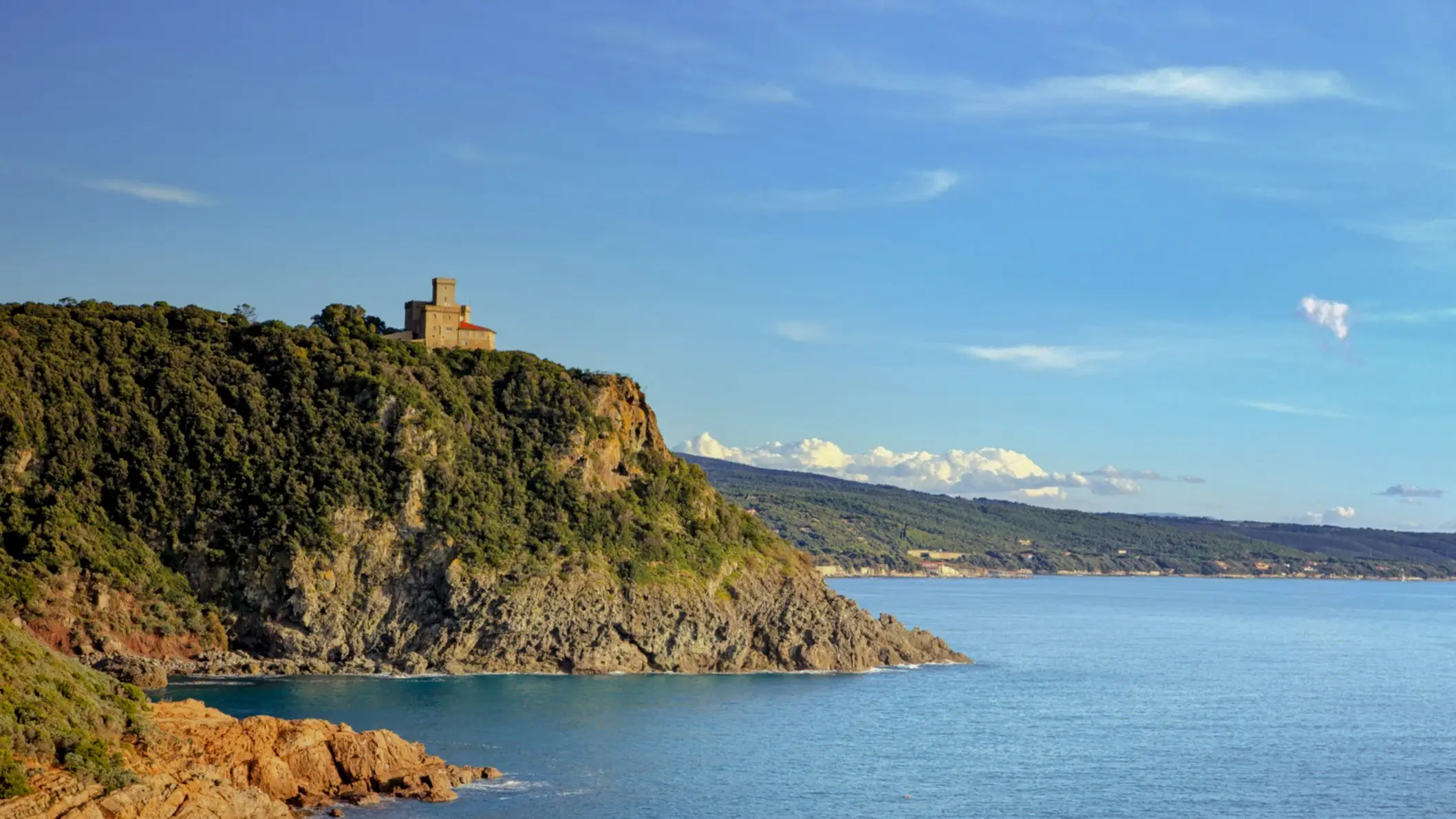 Italien, Toskana, Quercianella Klippen am Meer bei Sonne in Quercianella, Toskana, Italien mit einer Burg im Bild.