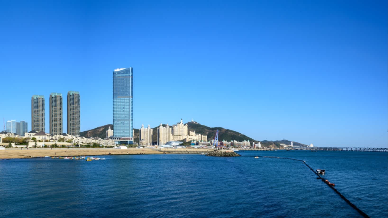 Vue sur la plage et la mer avec des buildings en arrière-plan, à Dalian, Chine.