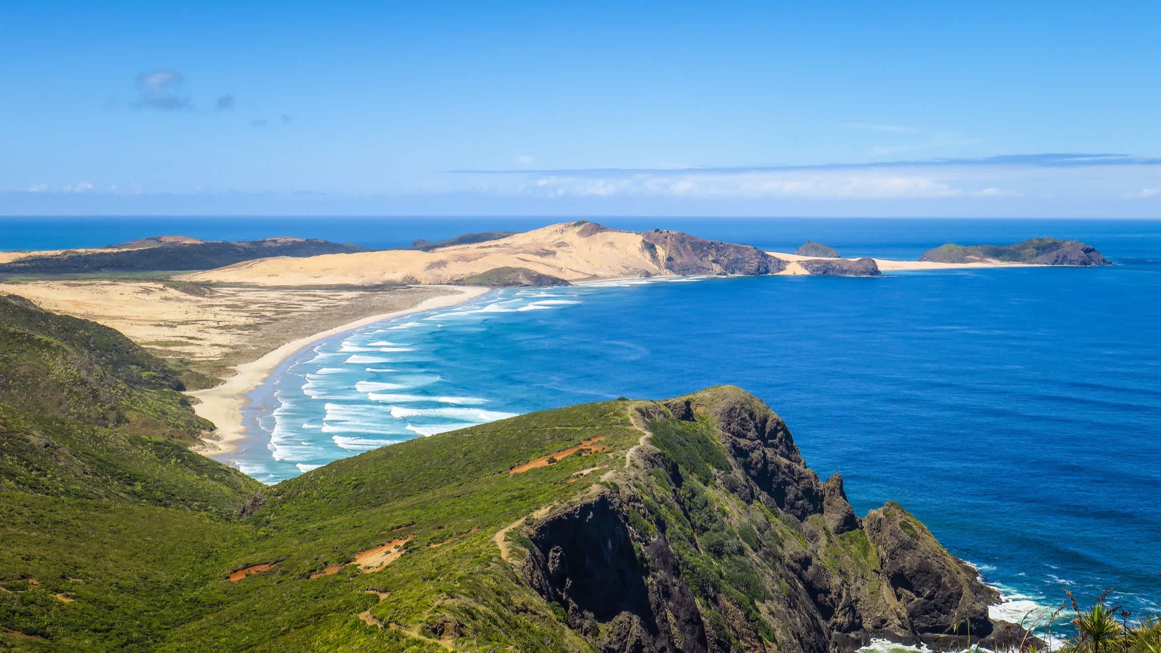 Der Strand Ninety Mile Beach, Cape Reinga, Neuseeland mit Blick von oben über die Bucht und auf das blaue Meer und die umliegenden Hügel.
