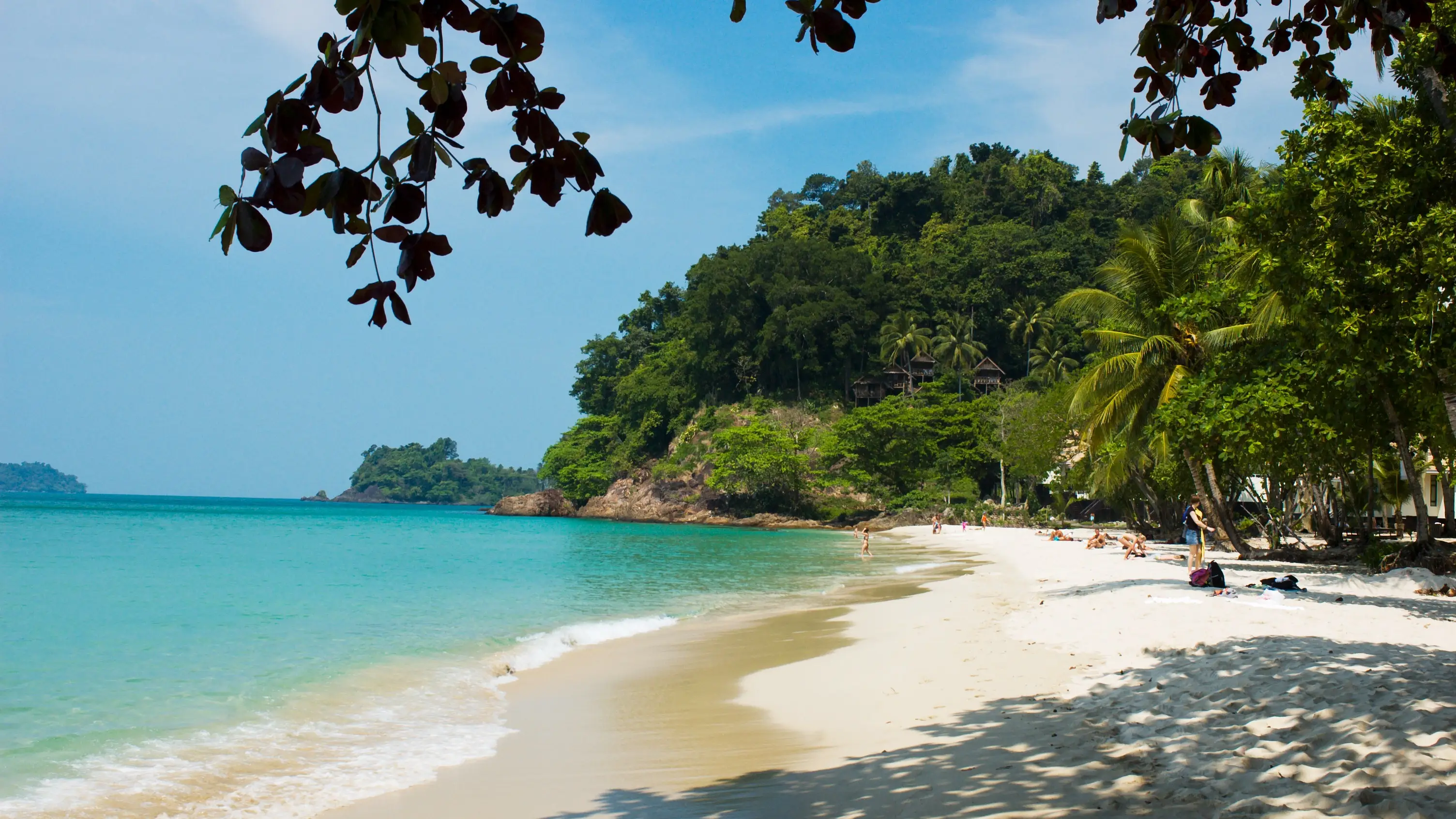 Ein ruhiger Strand mit türkisfarbenem Wasser und üppig bewachsenen Hügeln, Koh Chang, Thailand. 