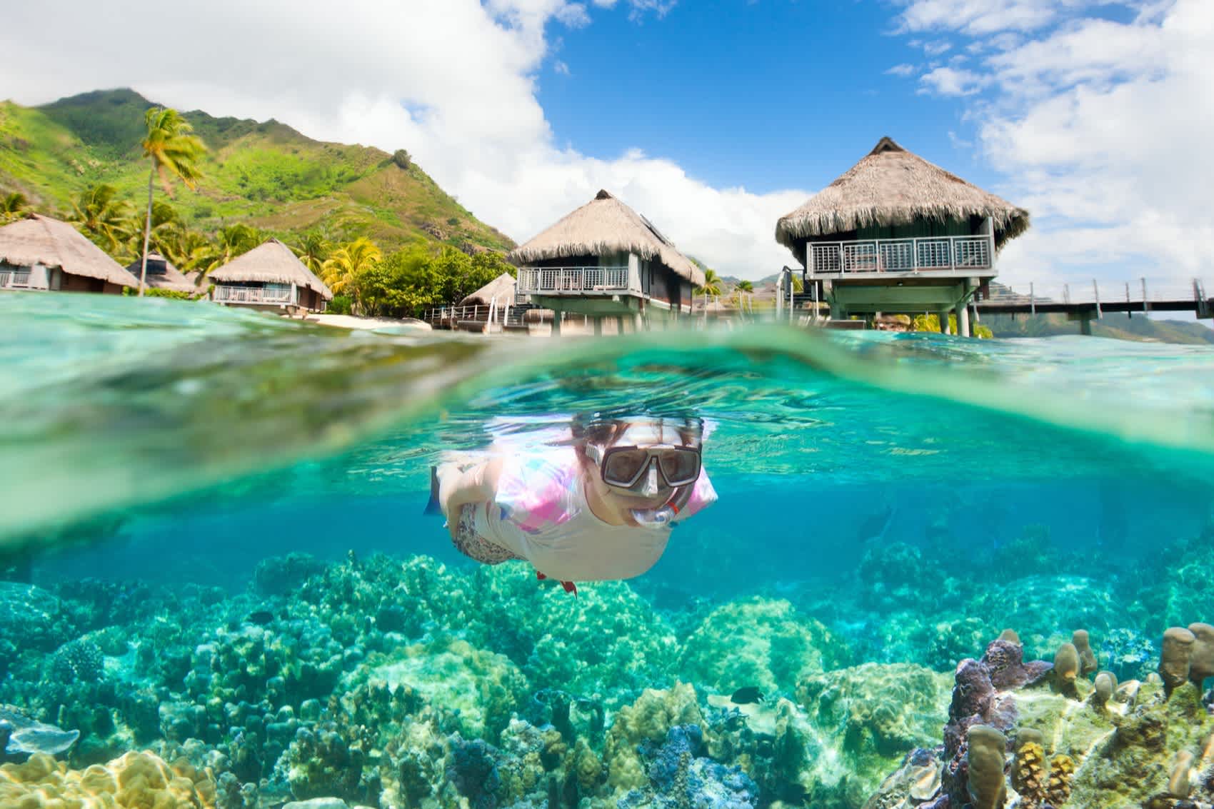 Frau schnorchelt mit Überwasserbungalows im Hintergrund