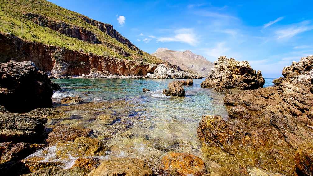 Vue sur l'eau cristalline entourée de rochers, dans la réserve naturelle de Lo Zingaro, en Sicile, en Italie.