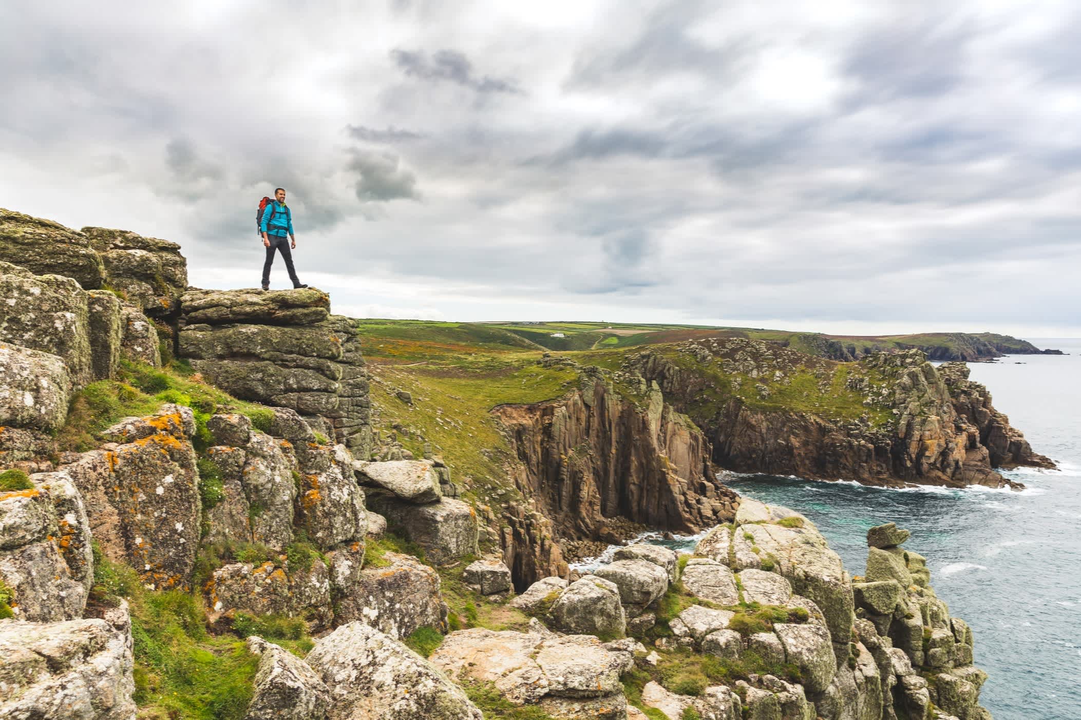 Mann auf eine Felswand in Cornwall, England. 