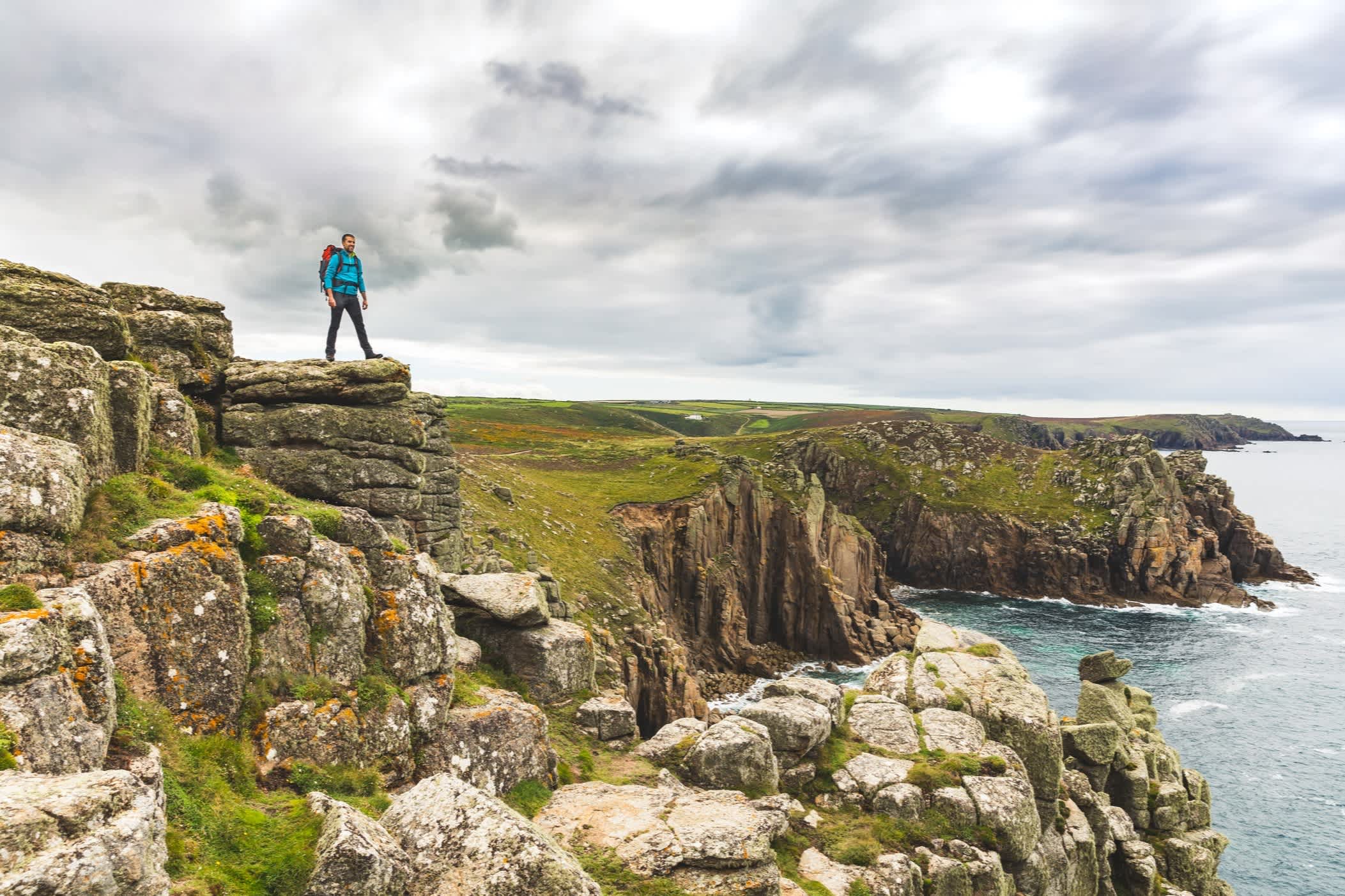 Homme sur une paroi rocheuse au bord de la mer en Cornouailles, Angleterre.