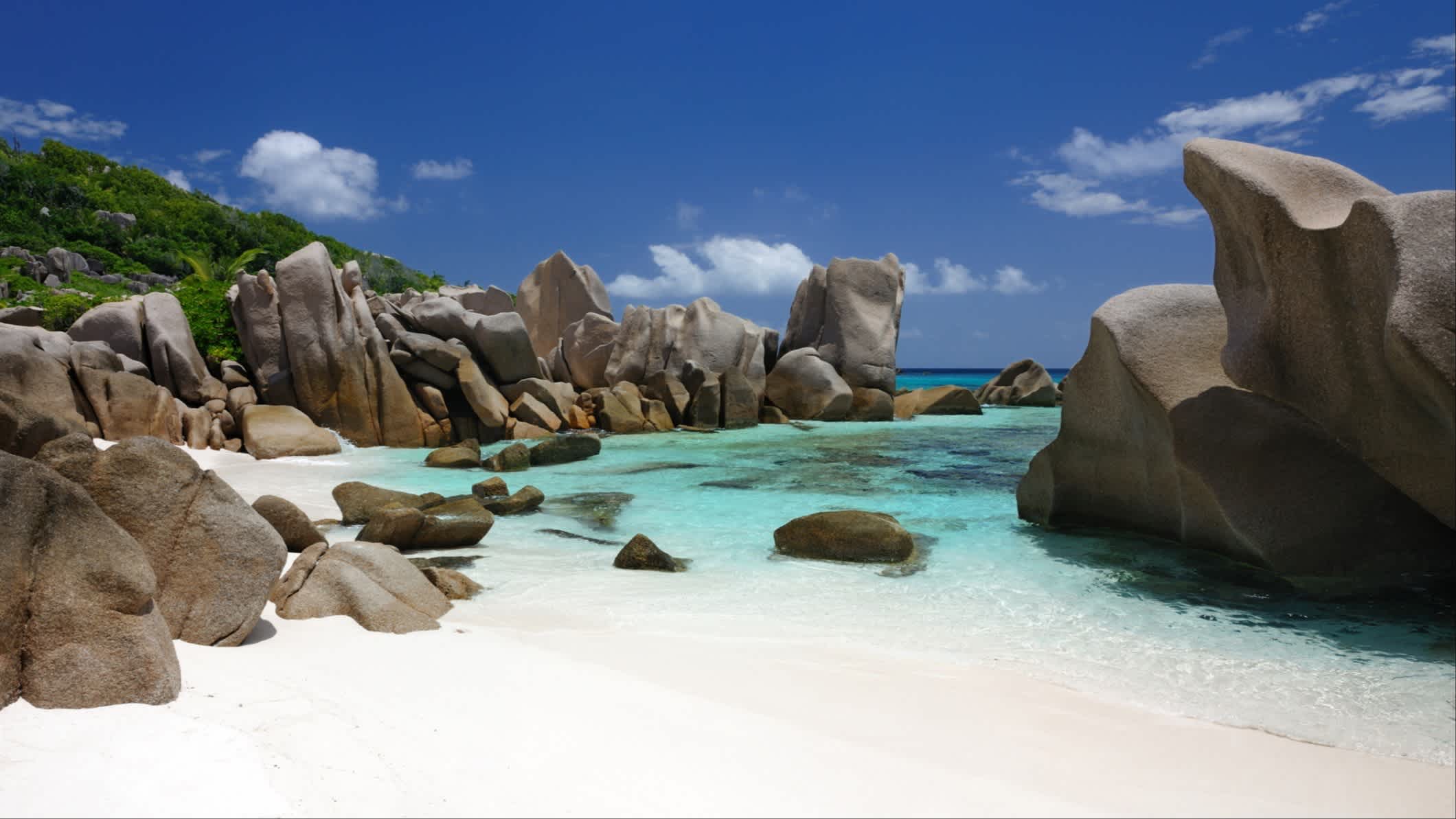 Die abgeschiedene Bucht von Anse Marron auf der Insel La Digue auf den Seychellen, bei sonnigem Wetter und mit den typischen Granitfelsen und kristallklarem Meereswasser im Bild.
