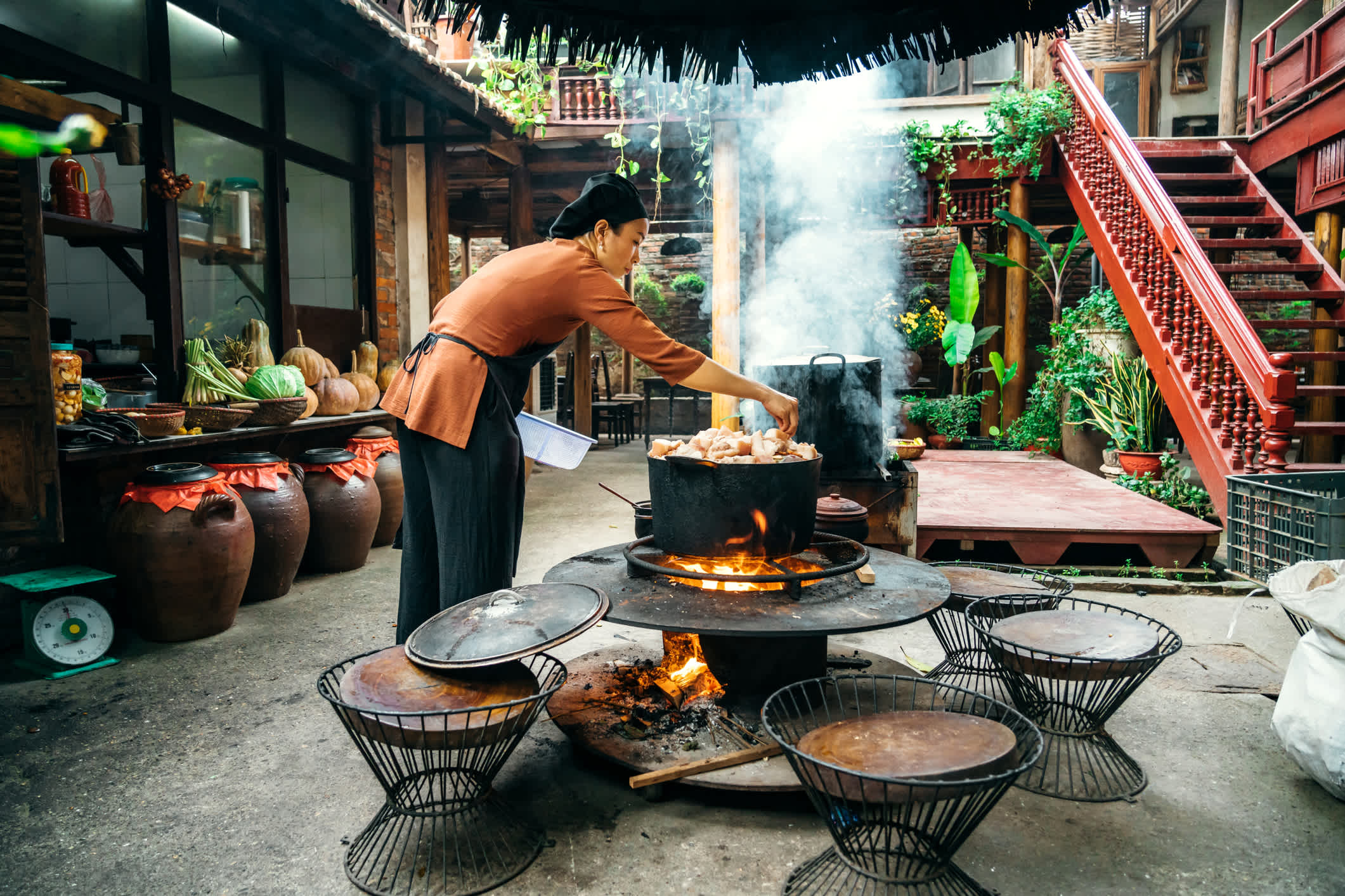 Junge Vietnamesin kocht gedämpften Fisch auf offenem Feuer im Restaurant