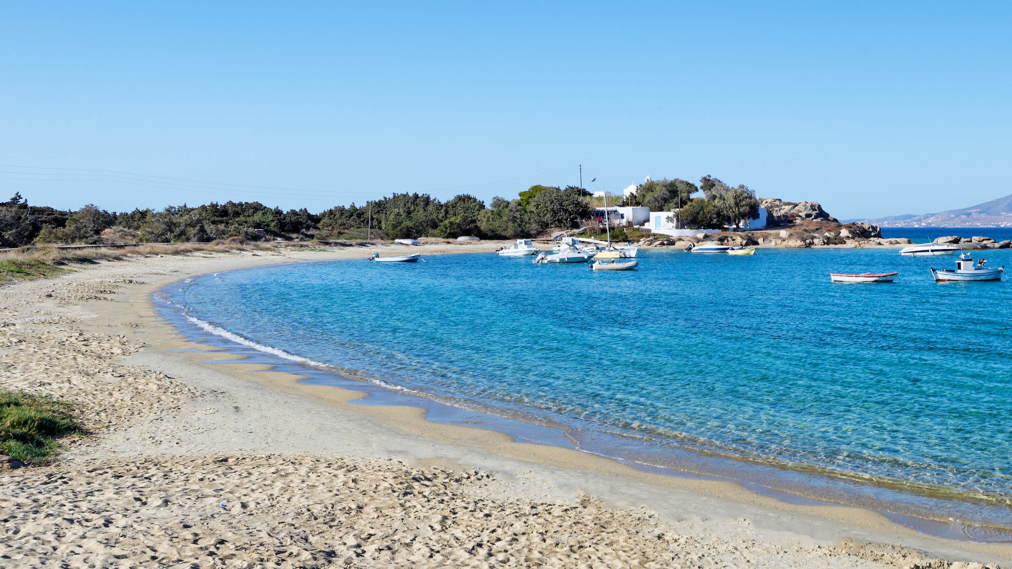 Vue sur la baie d'Agia Anna avec une plage de sable et des bateaux sur l'eau bleue azur, à Naxos, en Grèce.