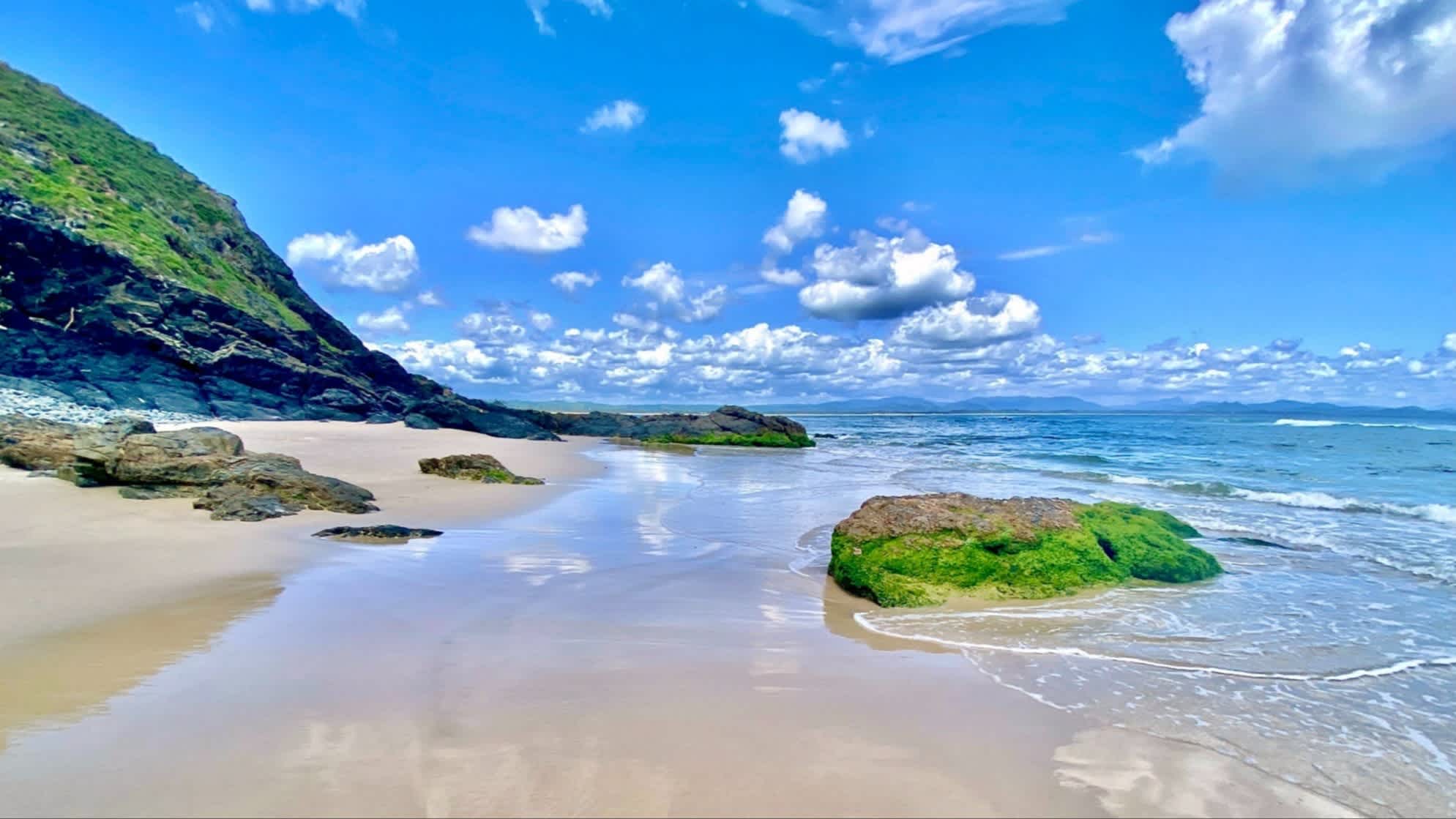 Landschaftsfoto von Himmel und Wolken, die sich auf dem nassen Sand am Little Wategos Beach spiegeln.