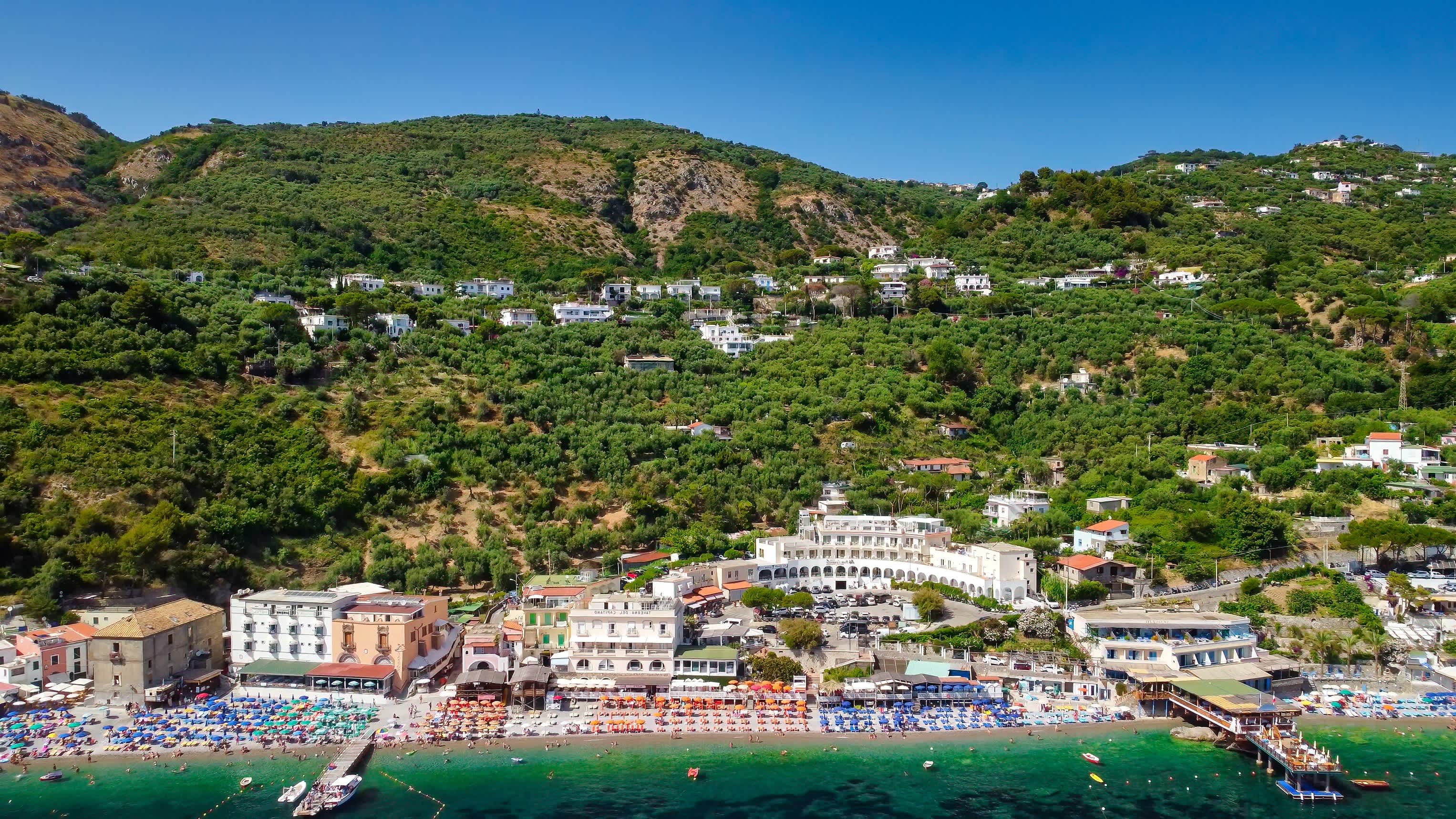 Luftaufnahme vom Strand Marina di Cantone mit grüner Hügellandschaft im Hintergrund