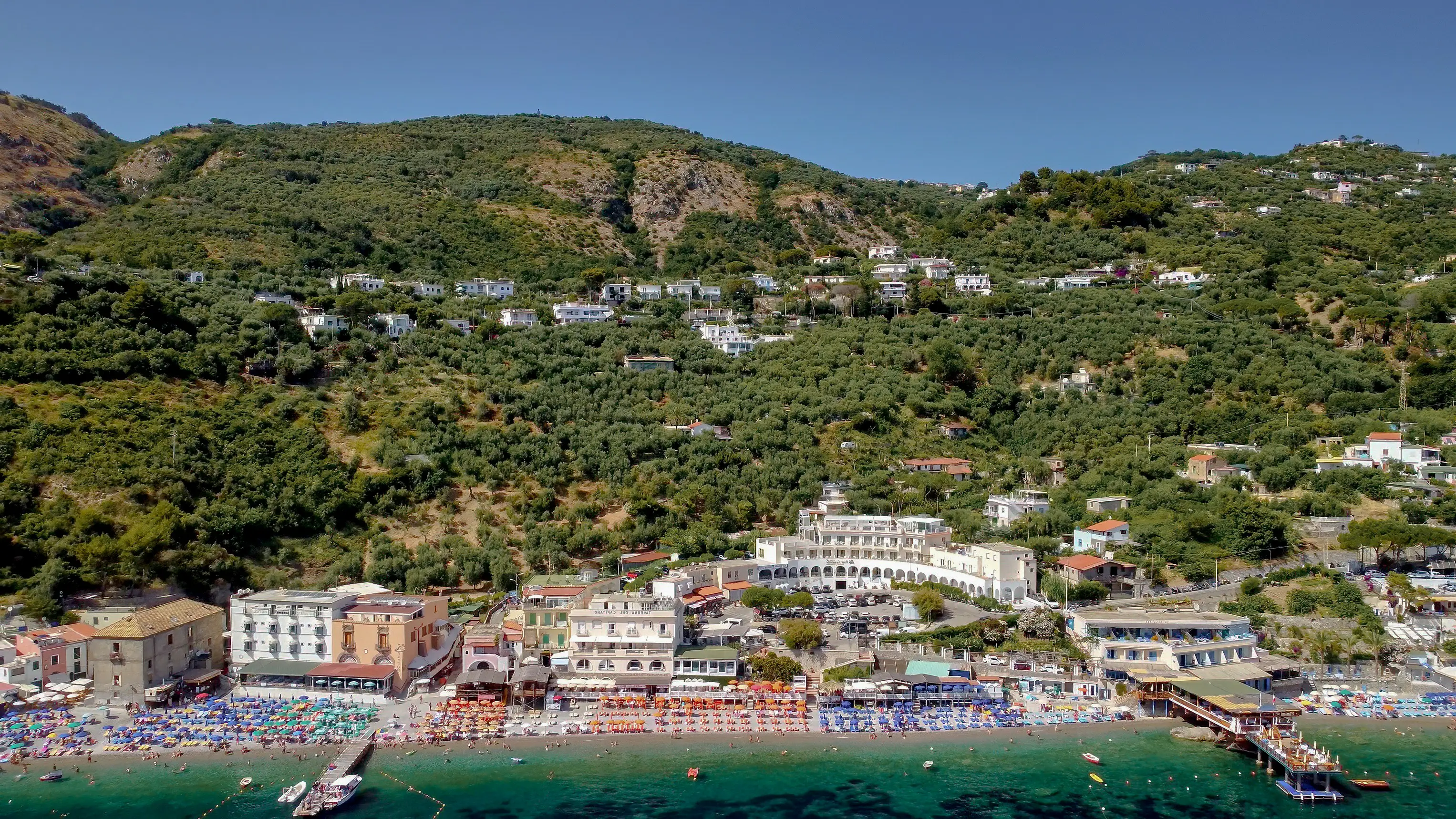 Aerial view of Marina di Cantone beach with green hilly landscape in the background