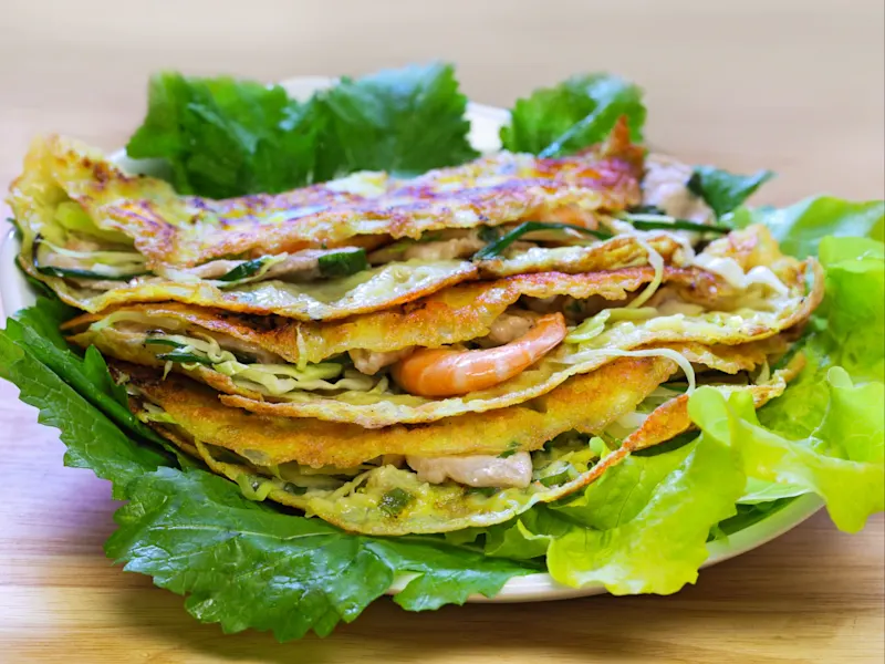 Nationalgericht Banh Xeo, Vietnam Banh Xeo sind knusprige vietnamesische Pfannkuchen, gefüllt mit Garnelen, Schweinefleisch und Gemüse, die traditionell mit frischen Kräutern und Dip-Saucen serviert werden