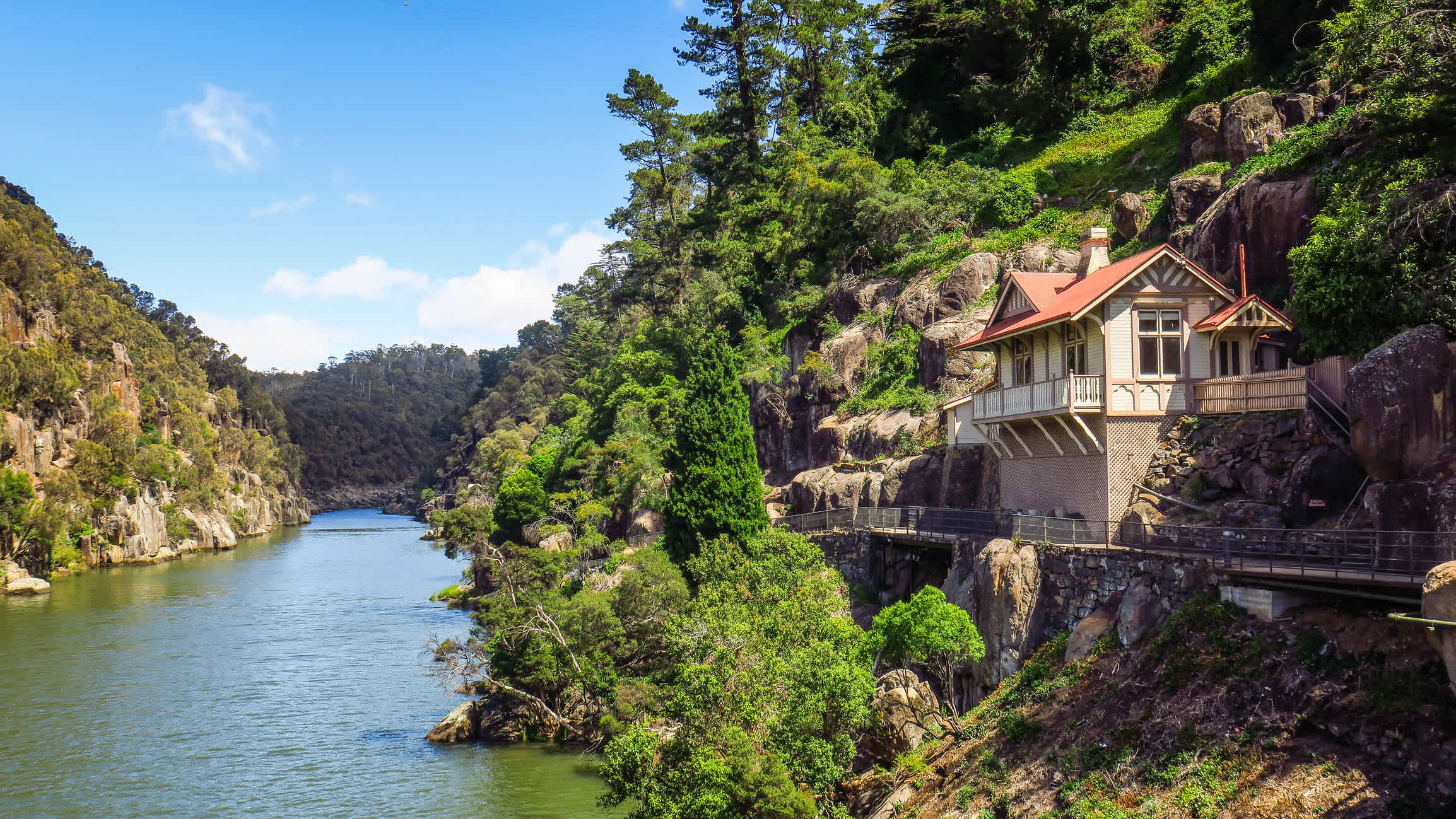 Australie, Tasmanie, rivière et route dans une région montagneuse avec une vieille maison à colombages construite dans la montagne.