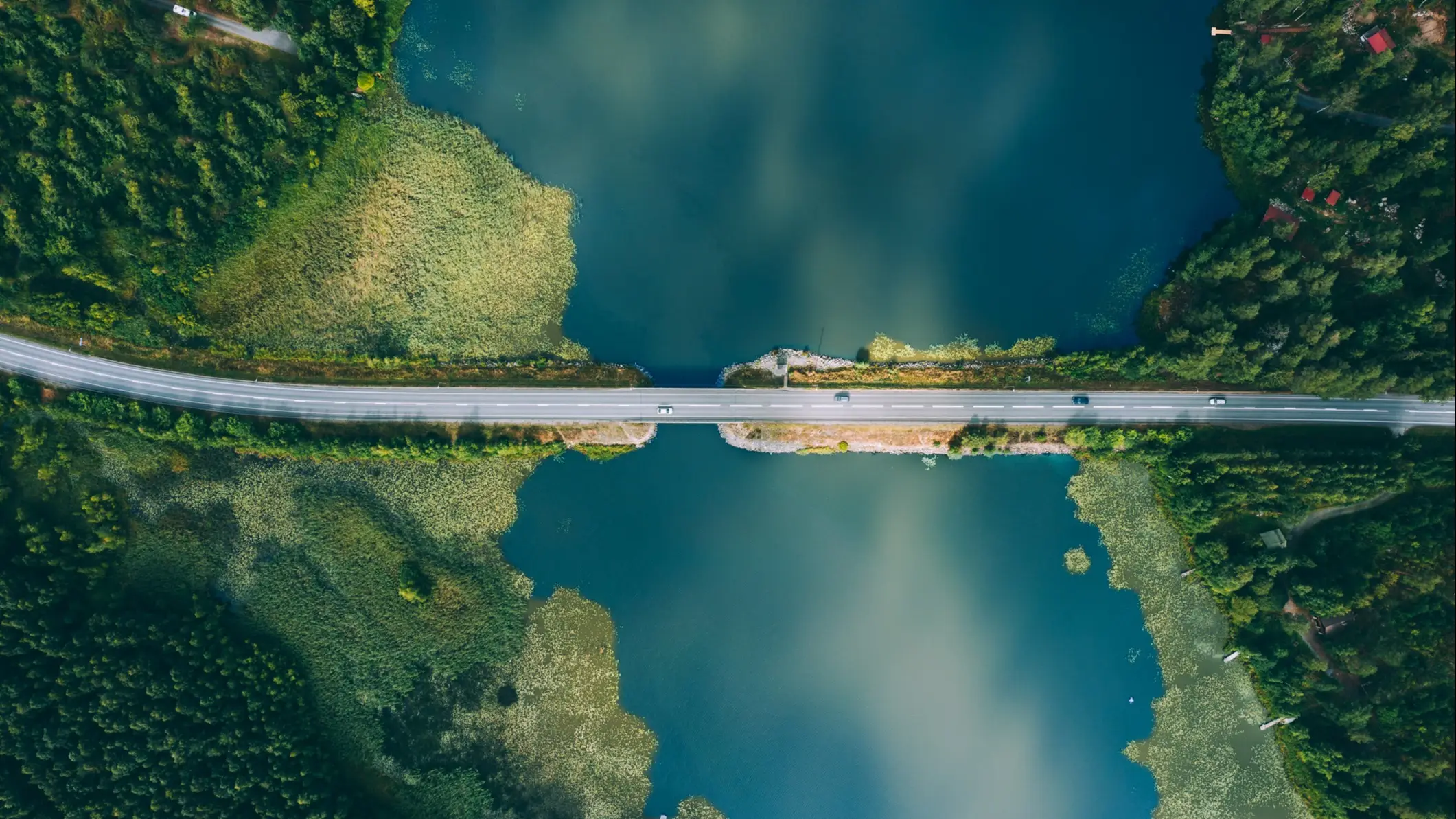 Südfinnland Luftaufnahme einer Straße über einem See, umgeben von Wald, Südfinnland, Finnland.