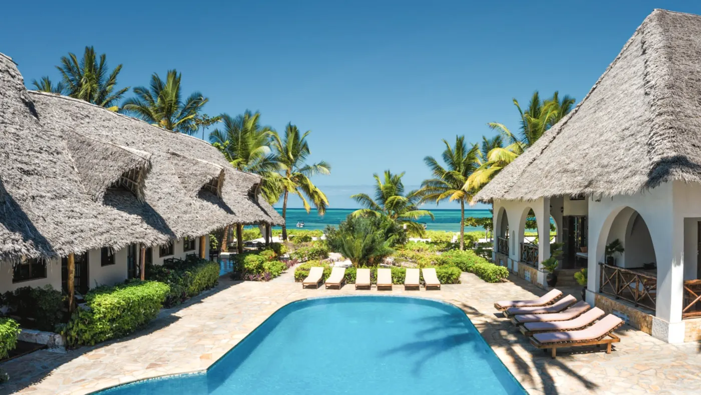 Pool mit Palmen und Strohdächern in Strandnähe. Zanzibar City, Unguja, Tansania.