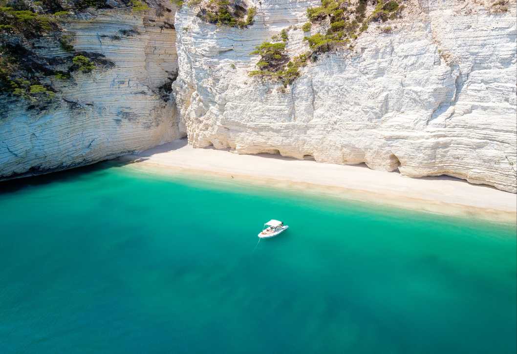 Petit bateau sur la mer turquoise du parc naturel Gargano 