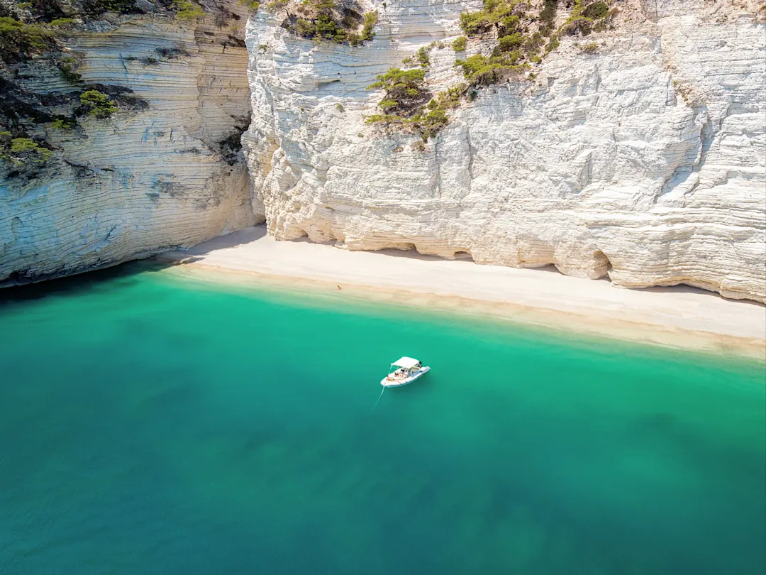 Kleines Boot auf dem türkisfarbenen Wasser des Naturparks Gargano