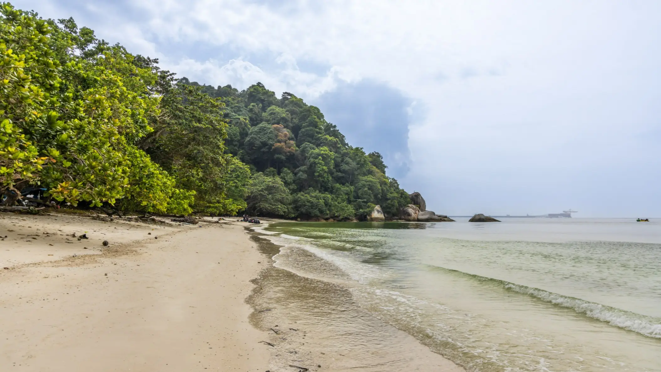 Sandstrand mit üppigem grünen Wald am Ufer und ruhigem Meer in Pulau Pangkor, Malaysia