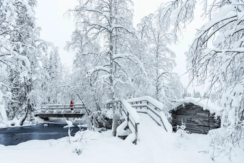 Hiking schnee FInnland Ein Wanderer steht auf der Brücke in der Nähe der Mühle, Akaslompolo, Finnland