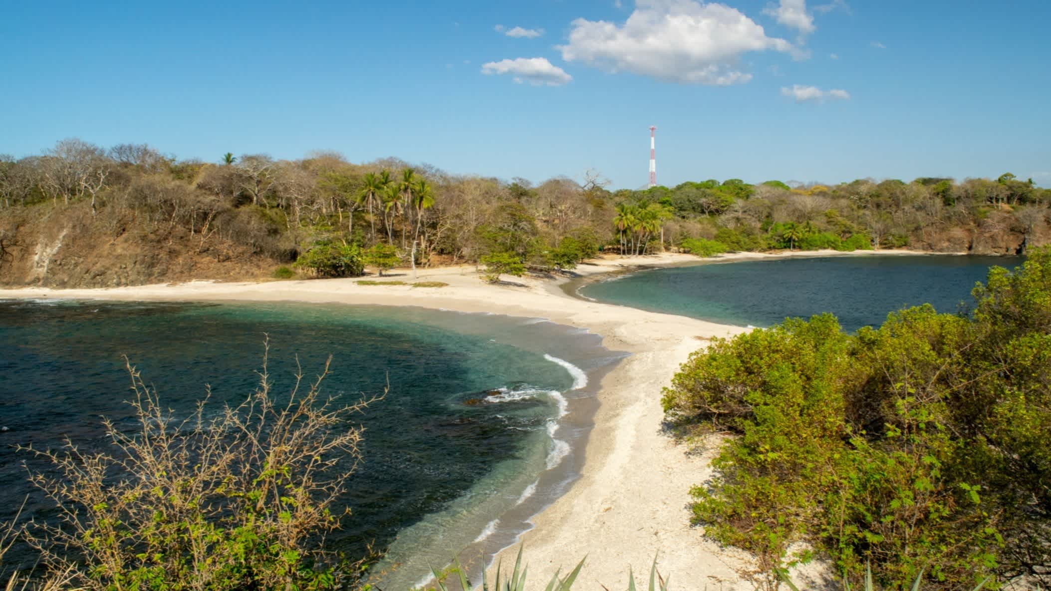 Der San Juanillo-Strand in Guanacaste, Costa Rica von oben mit Büschen auf beiden Seiten und bei Sonnenschein.