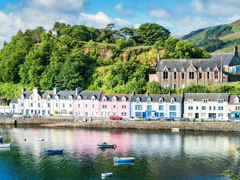 Schottland, Isle of the Skye, Portree Farbenfrohe Häuser am Wasser mit grünen Hügeln im Hintergrund. Portree, Isle of Skye, Schottland