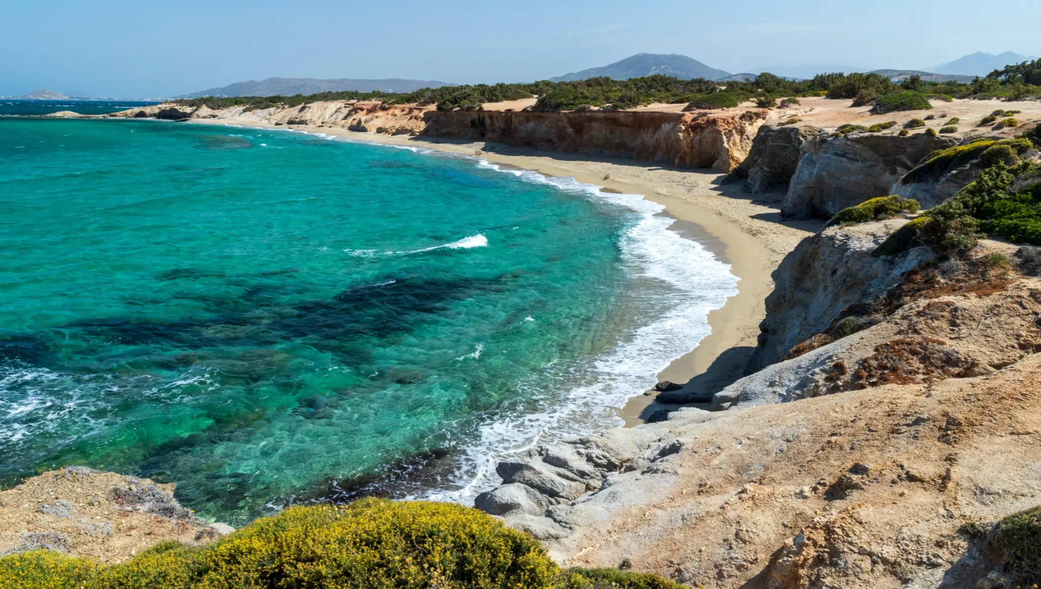 Griechenland, Naxos, Paralia Hawaii Blick auf den Sandstrand Paralia Hawaii in Naxos, Griechenland, umgeben von Felsen und türkisblauem Wasser.