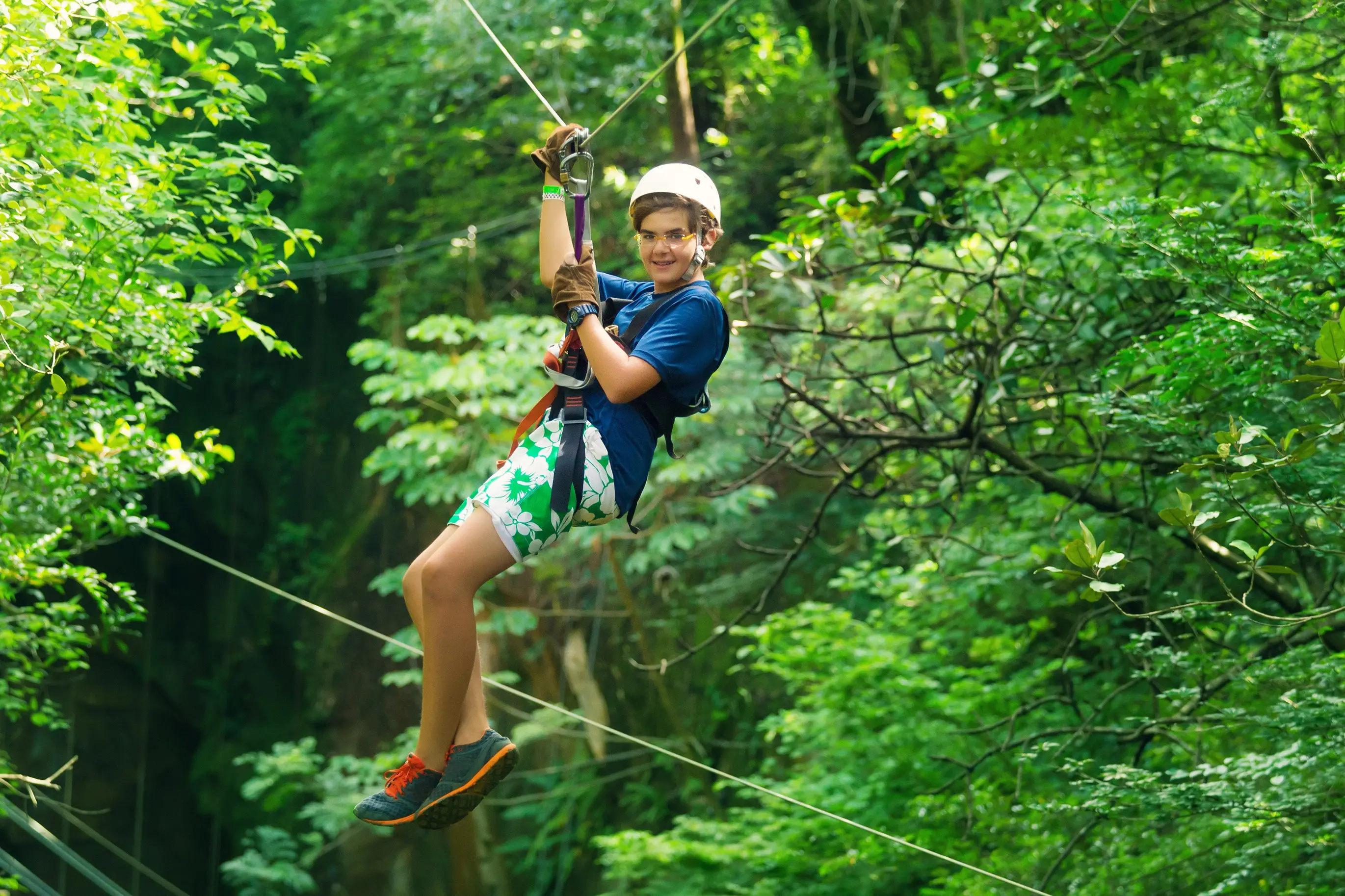 Thailand, Phuket, Zipline Ein Junge schwebt an einer Zipline durch den Dschungel