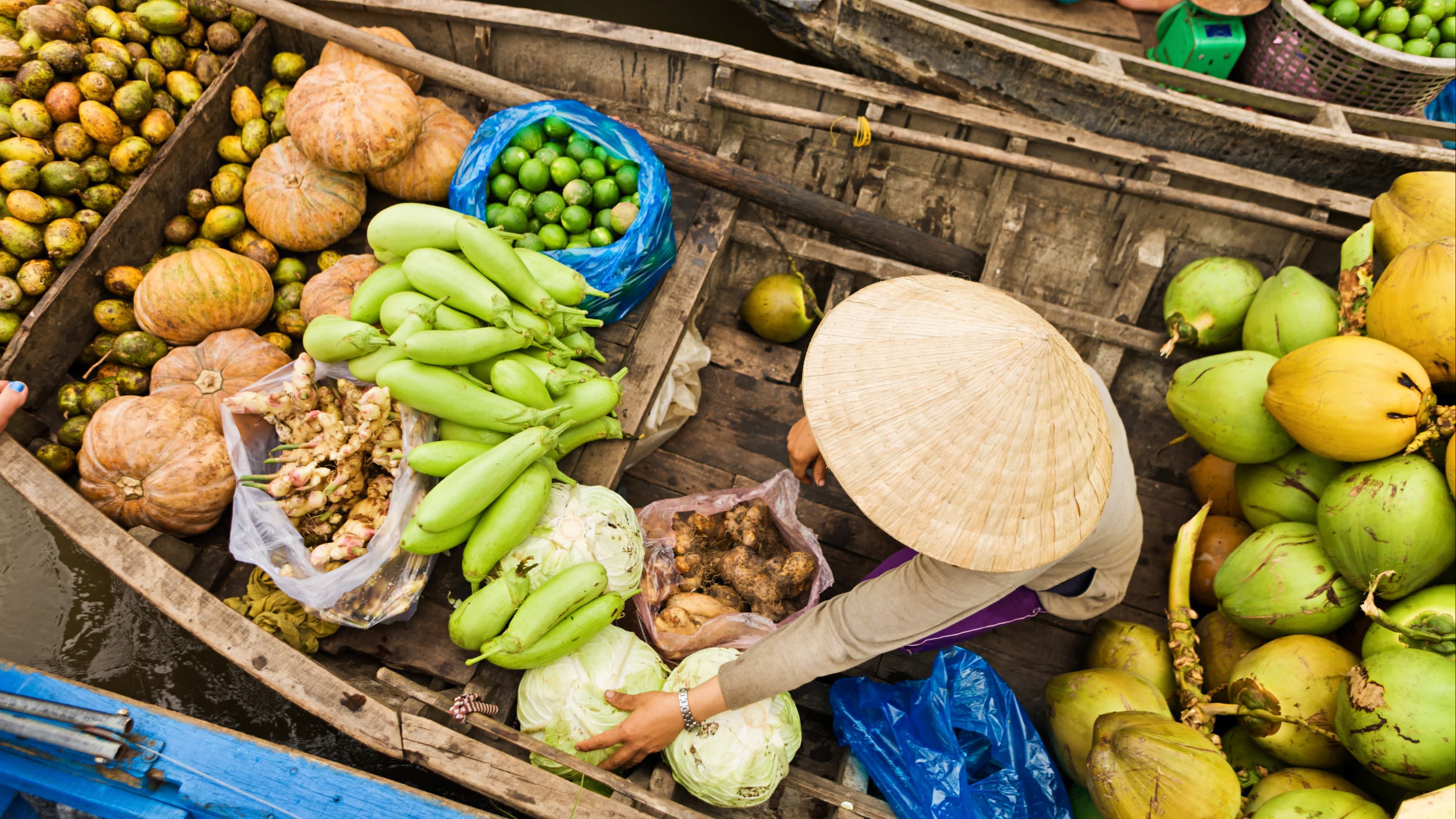 Vietnam, Delta du Mékong, Vendeuse Une femme marchande de légumes installée sur son embarcation traditionnelle en train de vendre sa marchandise pendant le marché du Mekong, sur le Delta du Mékong. Ne manquez pas ce marché mythique pendant votre voyage au Vietnam.