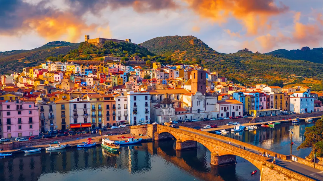 Bunte Häuser und alte Festung bei Sonnenuntergang. Bosa, Sardinien, Italien.