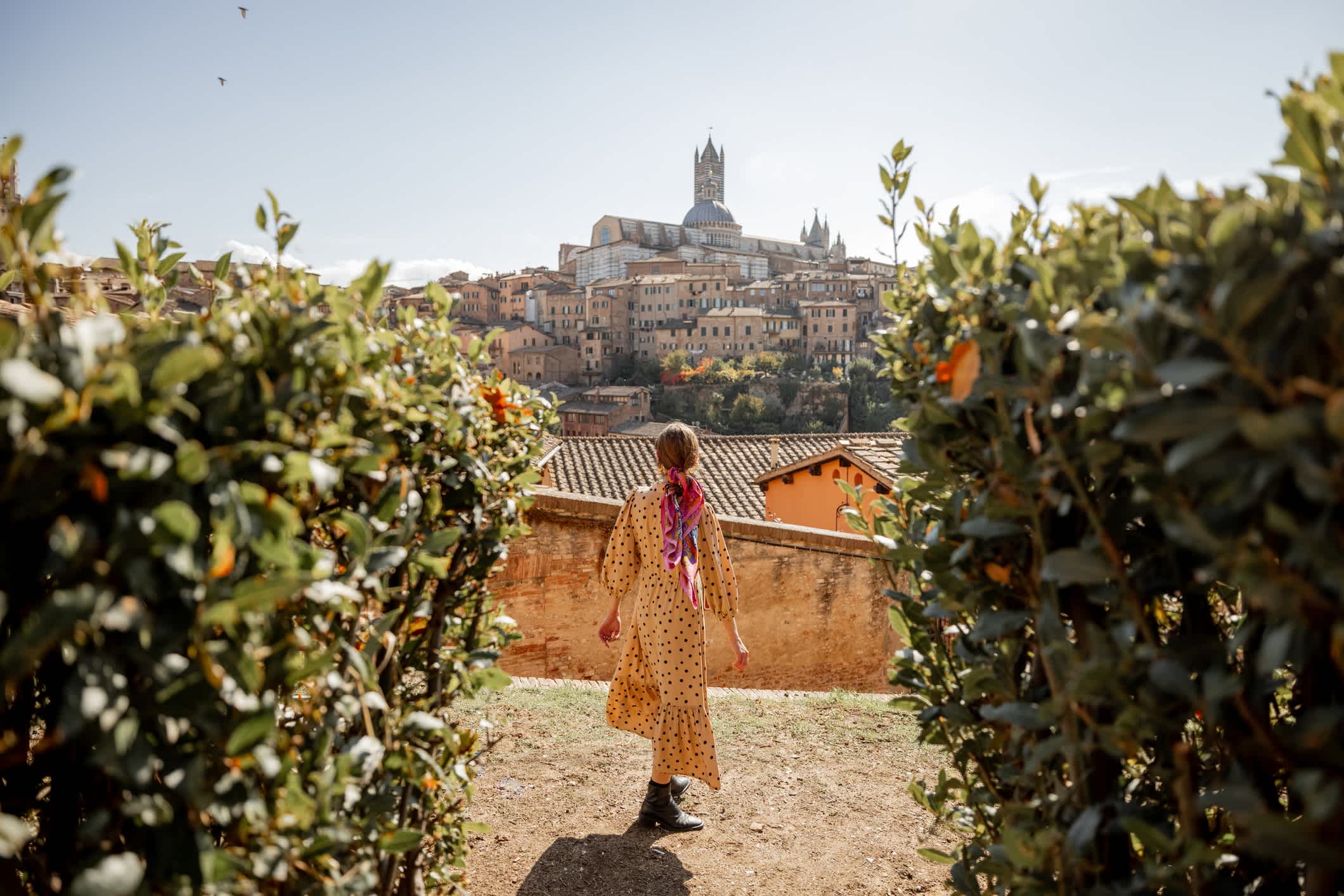 Eine Frau mit der Altstadt von Siena im Hintergrund, Toskana, Italien

