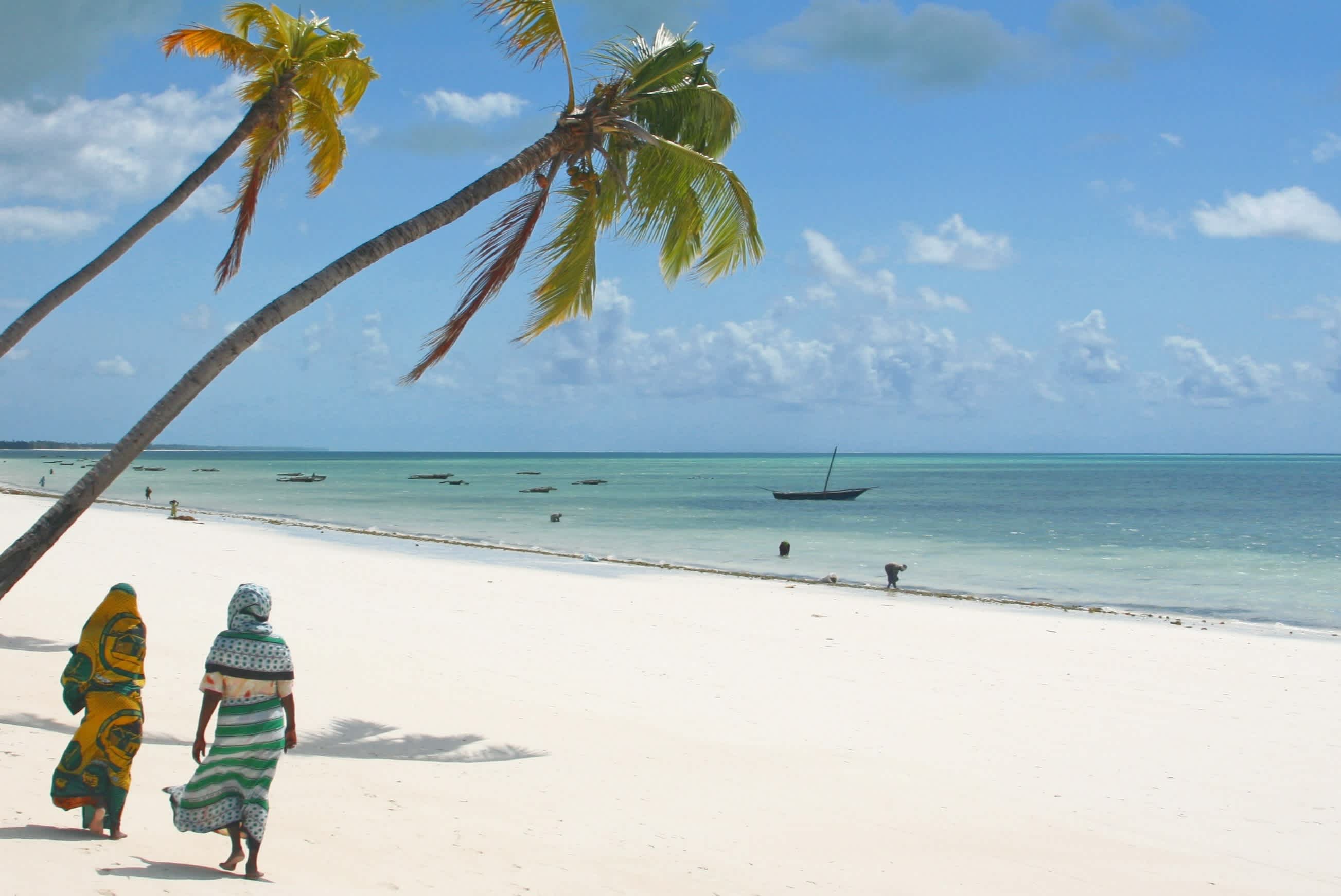Der Strand auf dem Insel Sansibar mit traditionell gekleideter Frau, Tansania. 