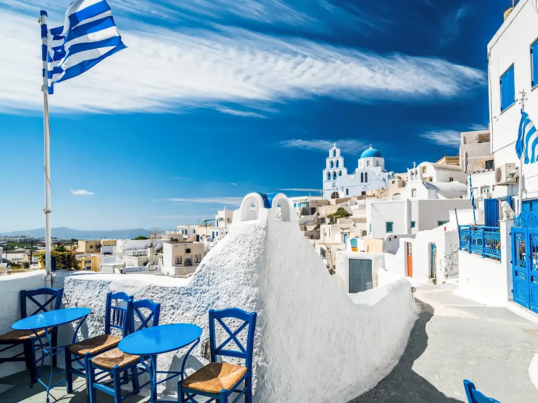 Traditionelle weiße Häuser mit blauen Dächern und griechischen Flaggen. Santorini, Kykladen, Griechenland.
