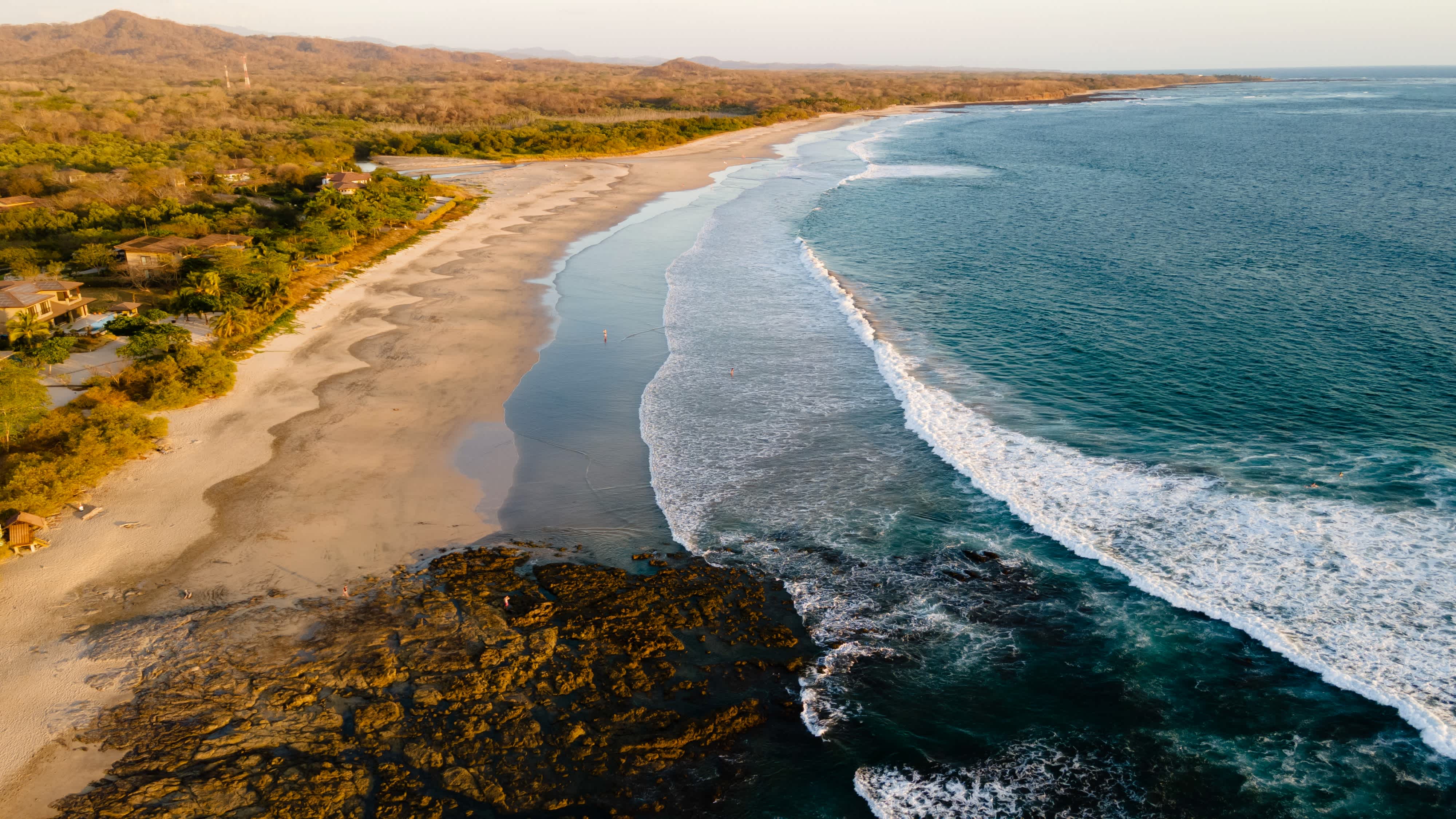 Blick aus der Luft auf den wunderschönen weitläufigen Strand von Avellanas in Guanacaste in Costa Rica mit welligem Meer und Felsen am Rand des Strandes. 
