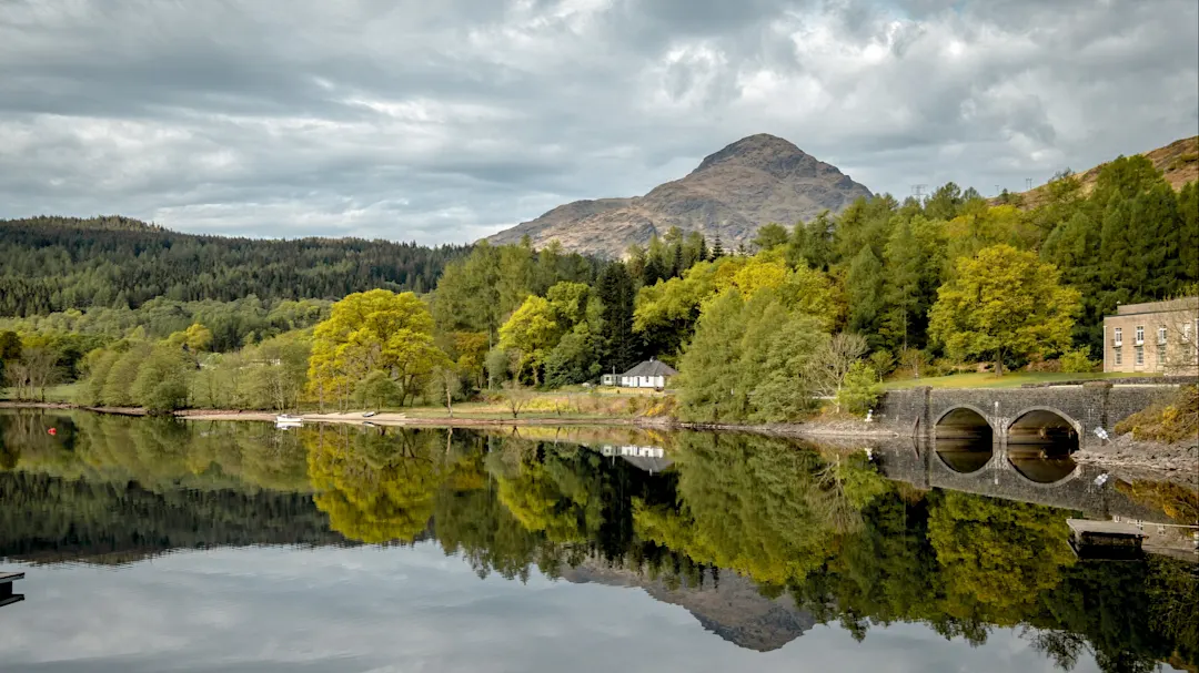 See mit Bergen und Brücke im Hintergrund. Loch Lomond, Schottland, Vereinigtes Königreich.
