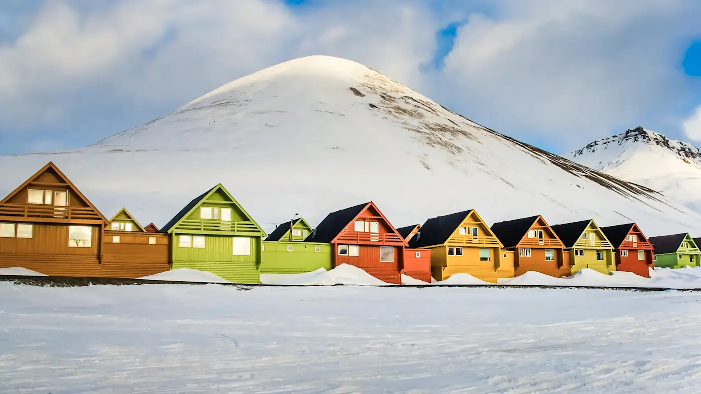 Maisons en bois colorées dans la neige devant des montagnes. Longyearbyen, Svalbard, Norvège.