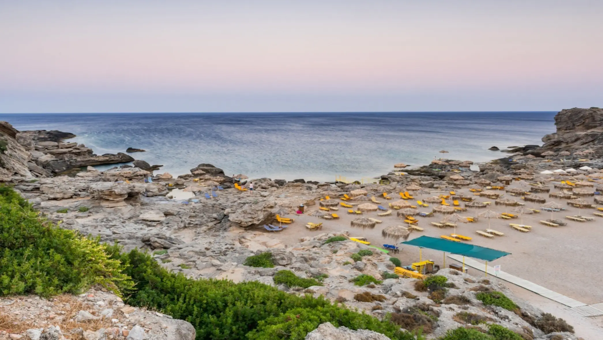 Parasols sur la plage de Kalithea au soleil couchant, Rhodes, Grèce.
