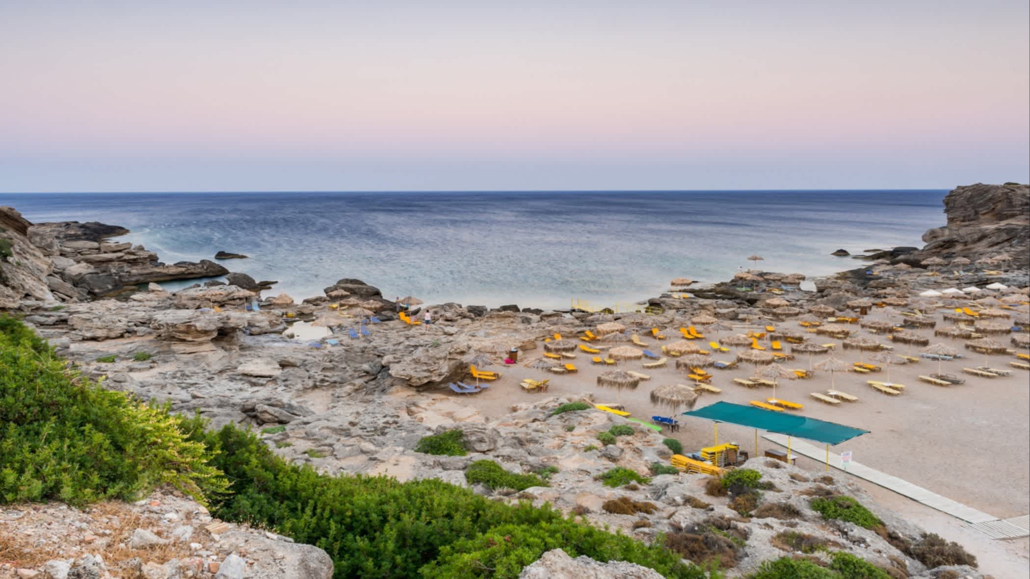 Parasols sur la plage de Kalithea au soleil couchant, Rhodes, Grèce.