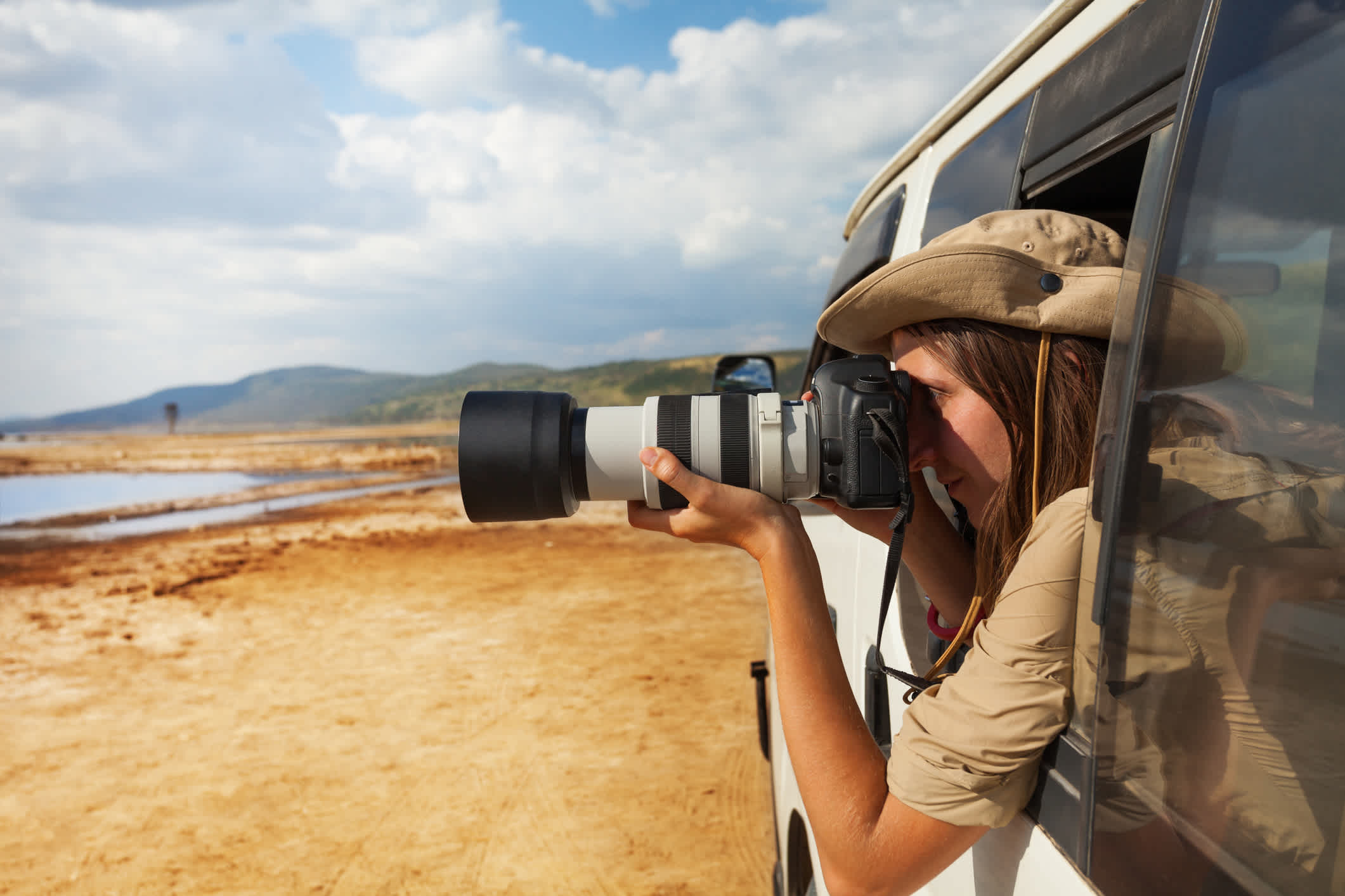 Une femme prend des photos depuis sa jeep lors d'un safari au Kenya