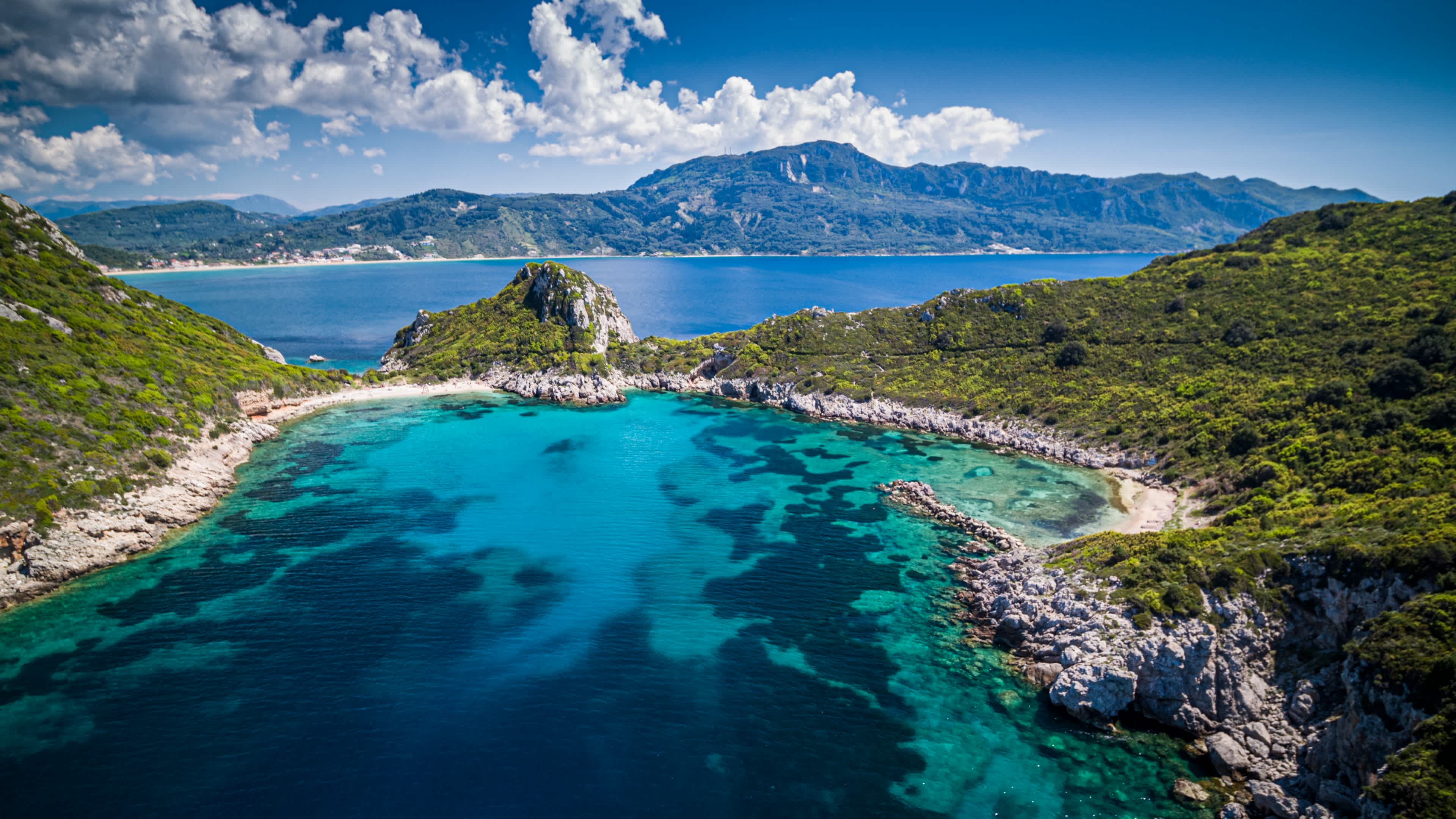 Vue aérienne de la plage de Porto Timoni à Corfou, en Grèce, avec ses falaises verdoyantes et ses eaux aux dégradés de bleu.