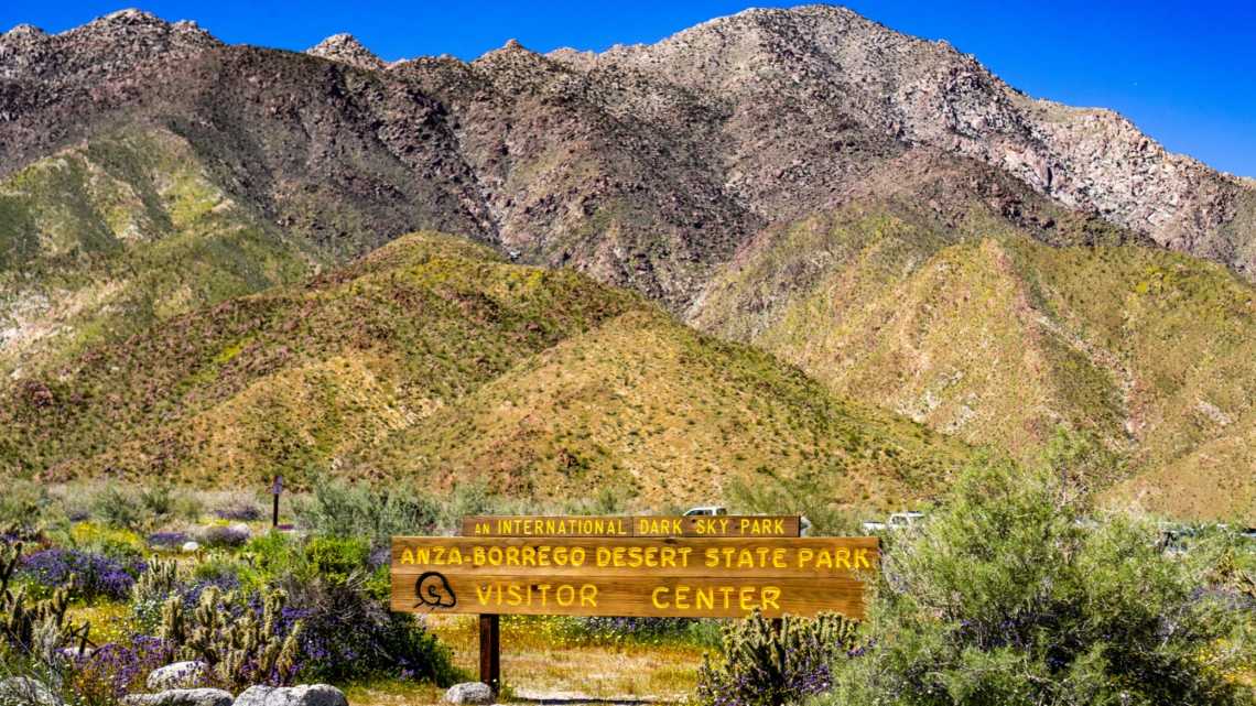 Schild des Anza-Borrego Desert State Park Visitor Center, umgeben von Wildblumen während einer Frühjahrsblüte, Südkalifornien