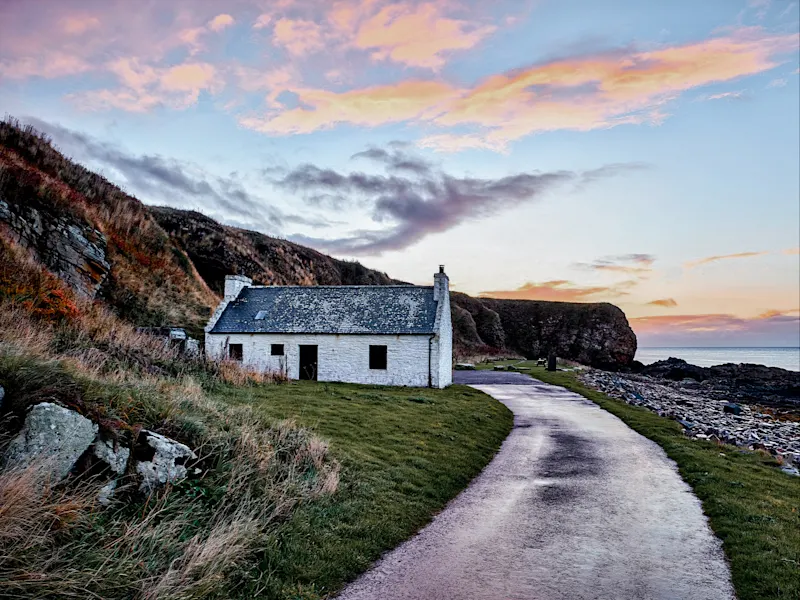 Scotland Small white church house on a steep cliff in Scotland, surrounded by green hills