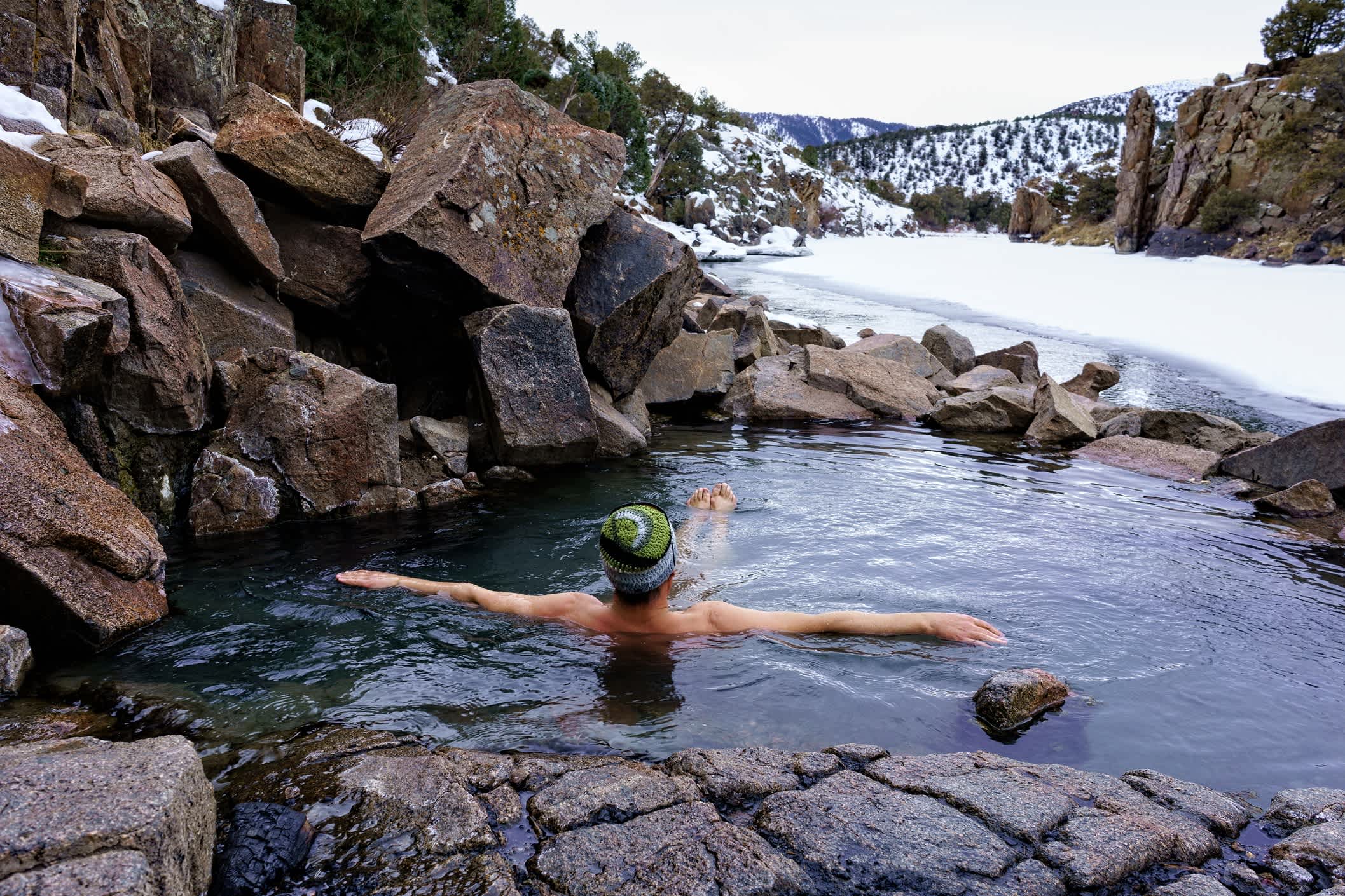 Mann genießen entspannende einweichen in natürlichen heißen Quellen im Winter auf dem Colorado River