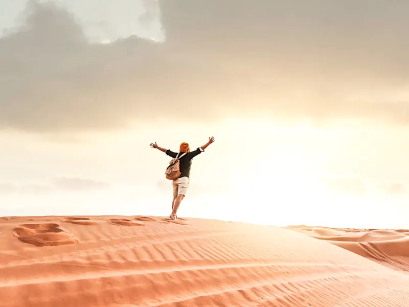 Homme pieds nus dans le désert au coucher du soleil, Wahiba Sands, Sharqiya, Oman.