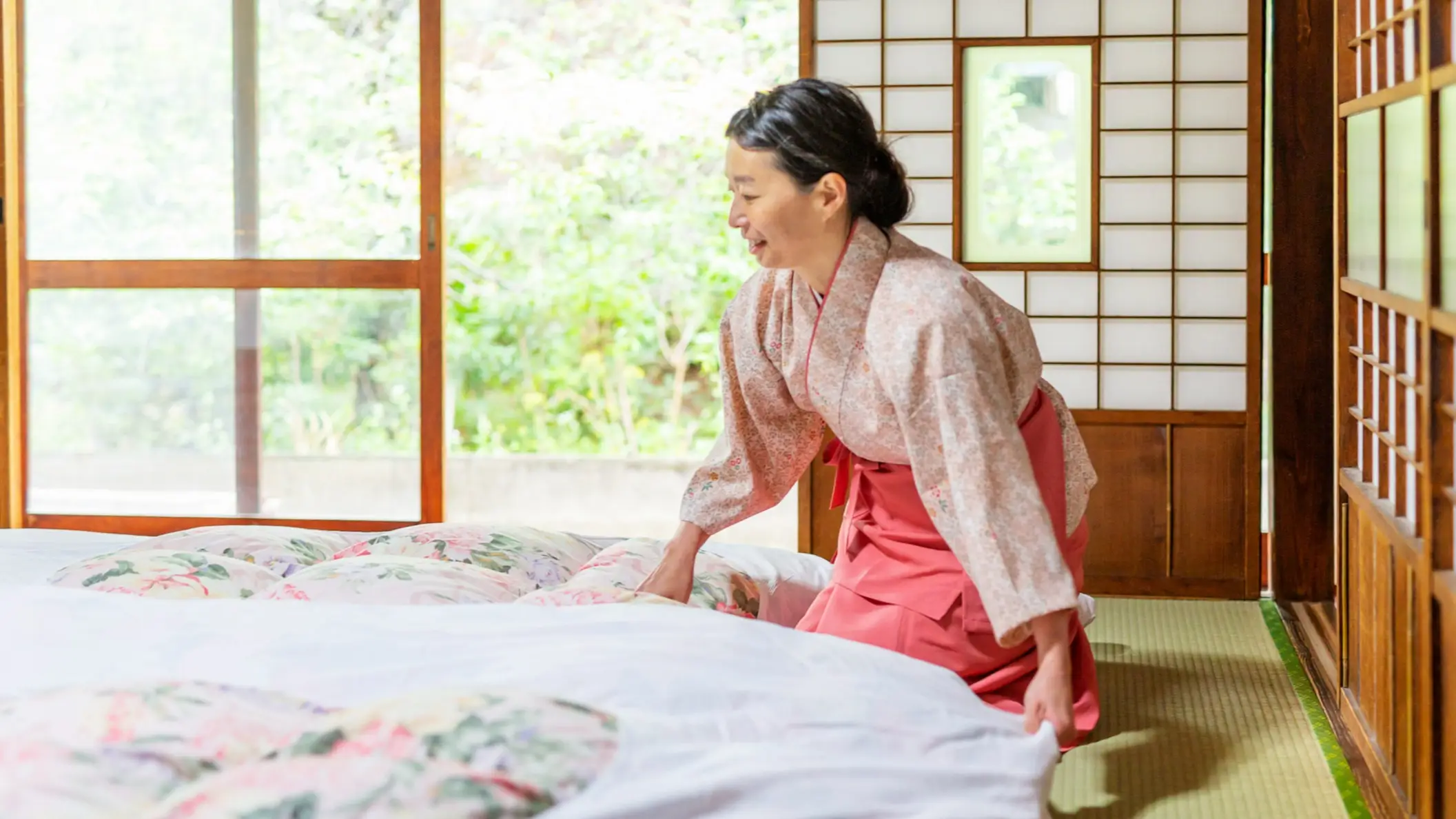 Une femme japonaise fait un lit futon traditionnel dans un ryokan.