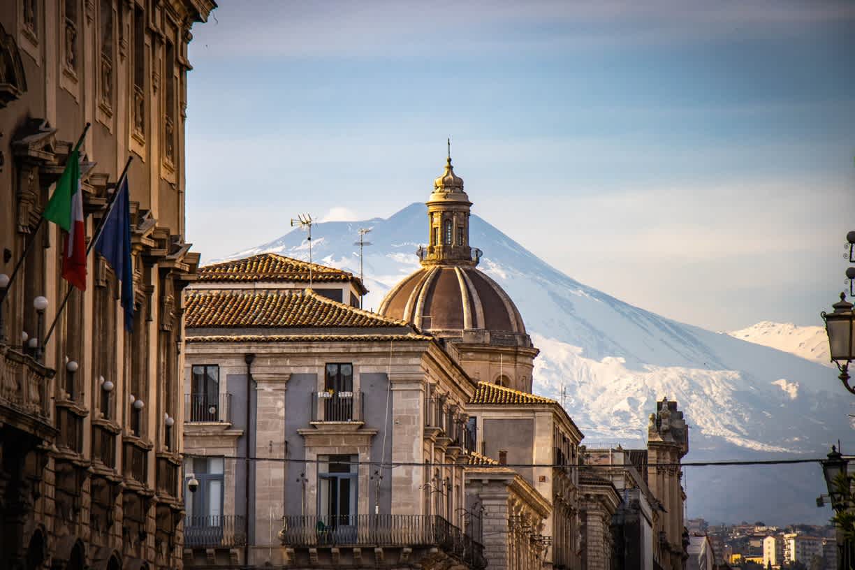 Historische Gebäude in Catania mit schneebedecktem Etna im Hintergrund