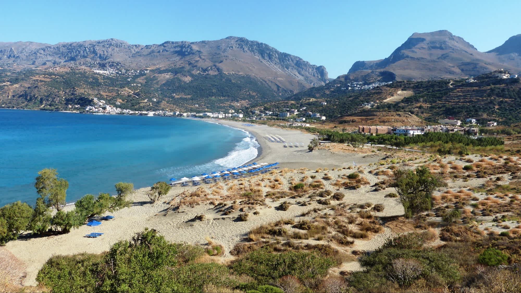 Blick auf den Sandstrand von Plakias, Rethymon, Kreta, Griechenland mit Blick über die Bucht und das Gebirge im Hintergrund.